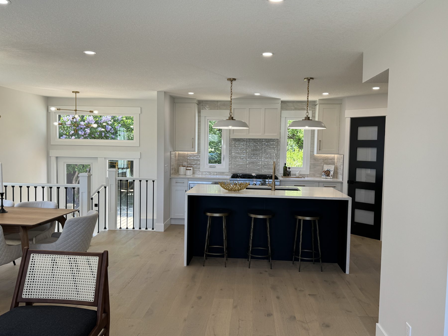 Modern kitchen renovation with island, white cabinets, and wood floors — Lake Bonavista by Onsite Contracting Services