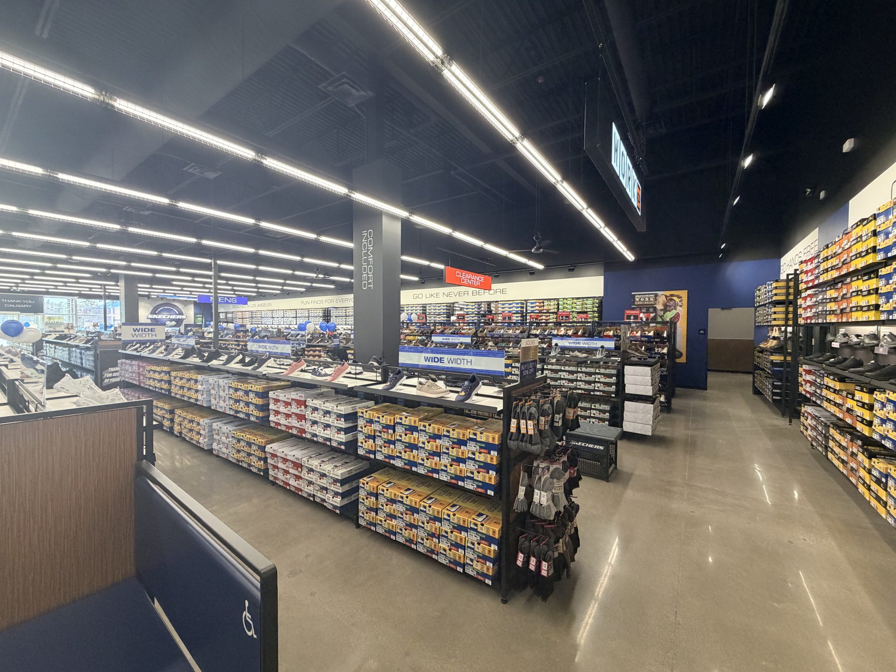 Shoe store with shelves of boxes, shoes on display, and lighting — Skechers (Signal Hill)