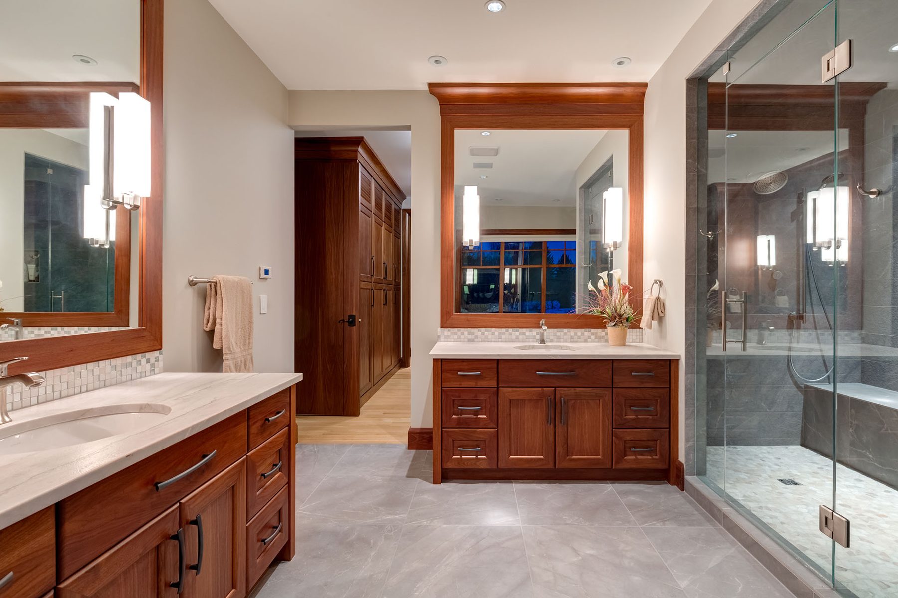 Luxurious bathroom renovation with wooden vanities, marble countertops, and glass shower — Oxford