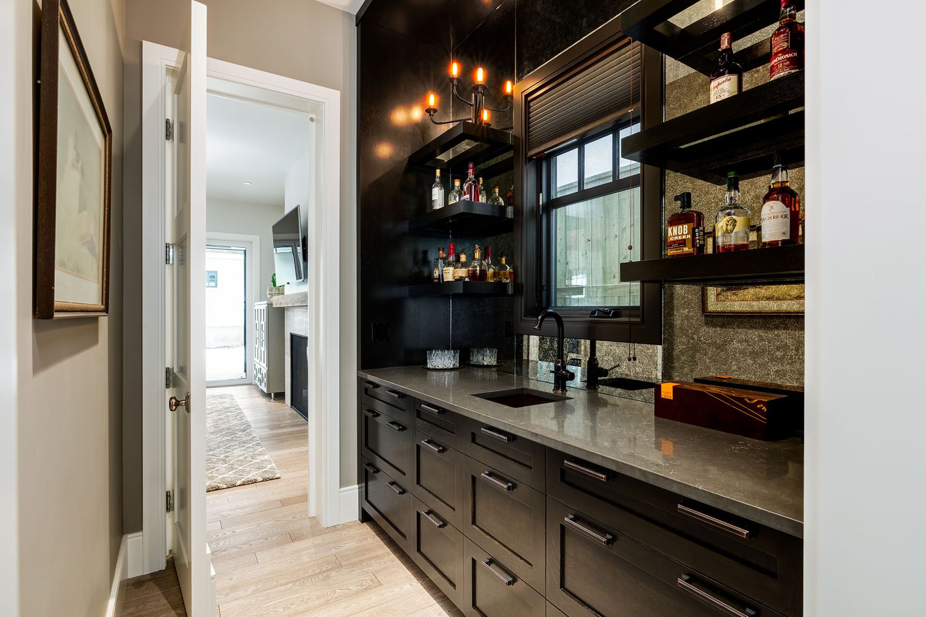 Modern bar area with dark cabinetry, stone countertops, and liquor bottles — Cleret Velour