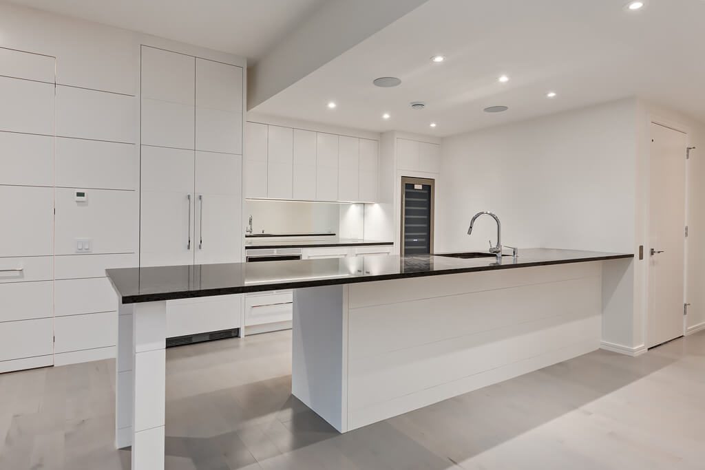 Modern kitchen island with waterfall counter, sleek cabinets, and sink — Blanc de Blanc