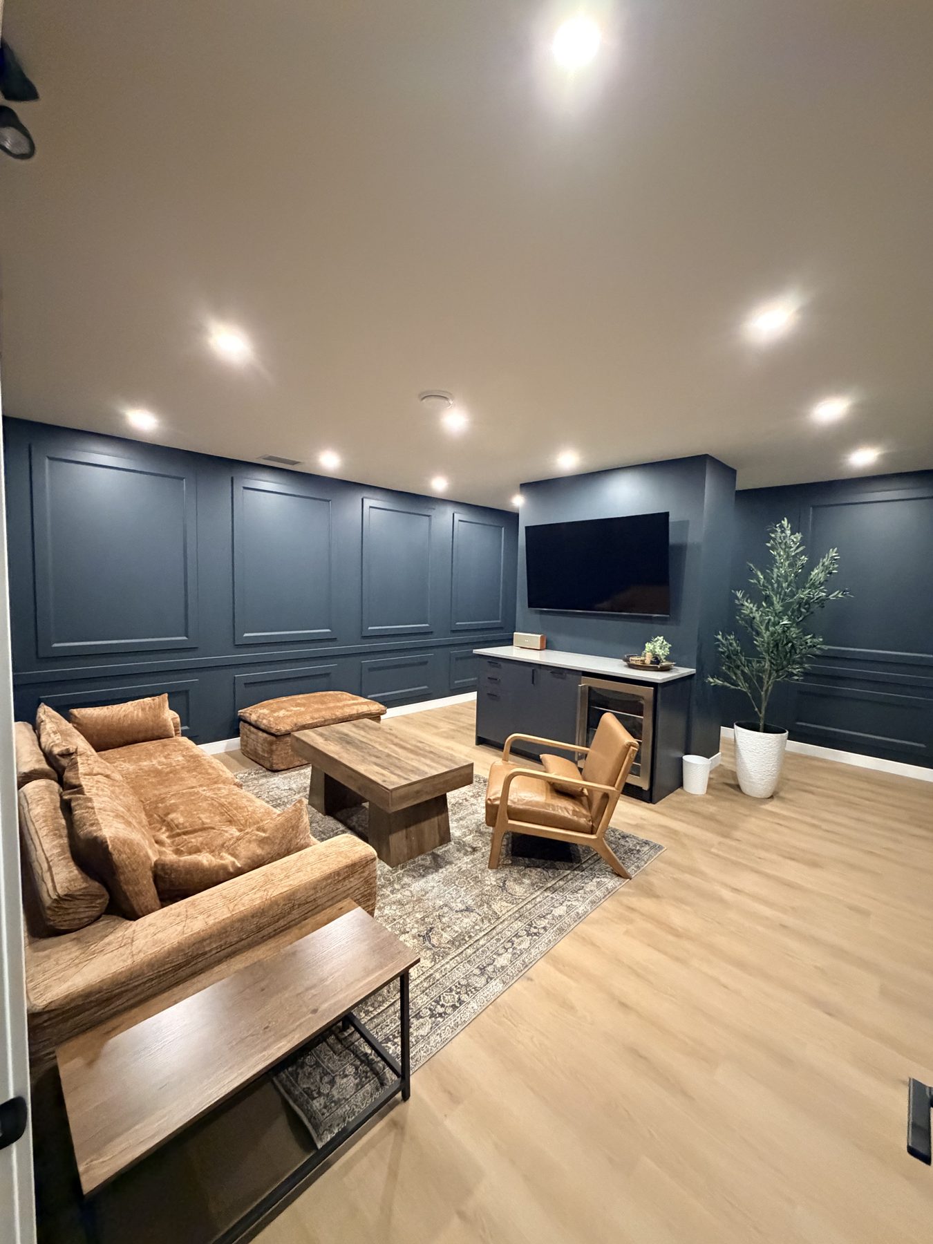 Basement renovation with navy paneled walls, wood floors, and modern furniture — The Barron Venue