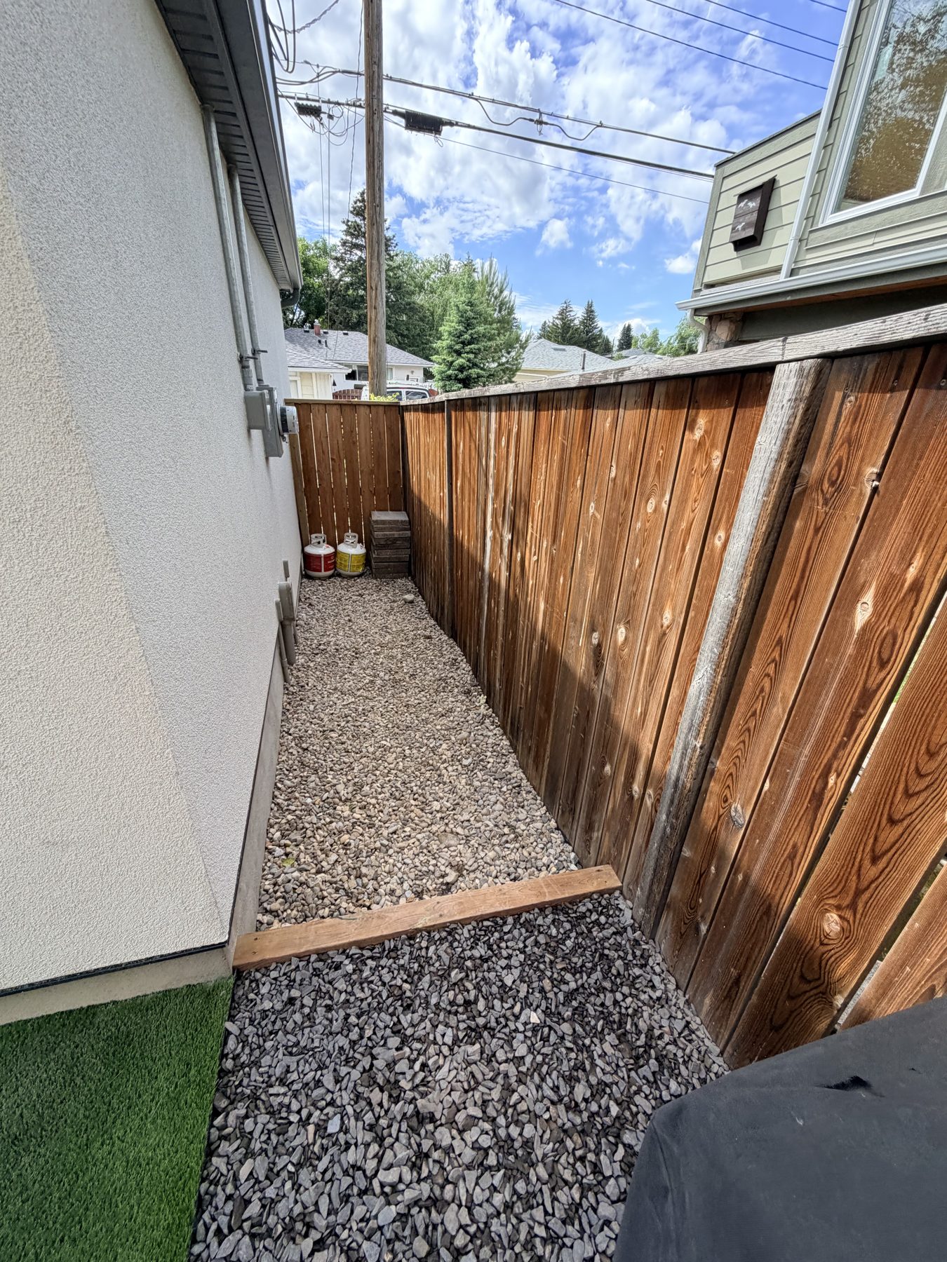 Gravel yard with gas tanks next to stucco wall and wood fence — 3505 41 Street SW, Calgary