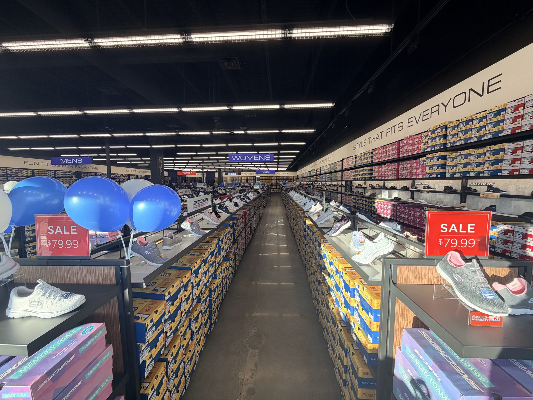 Shoe store aisles stocked with boxes, shoes on display, sale signs — Skechers (Signal Hill)
