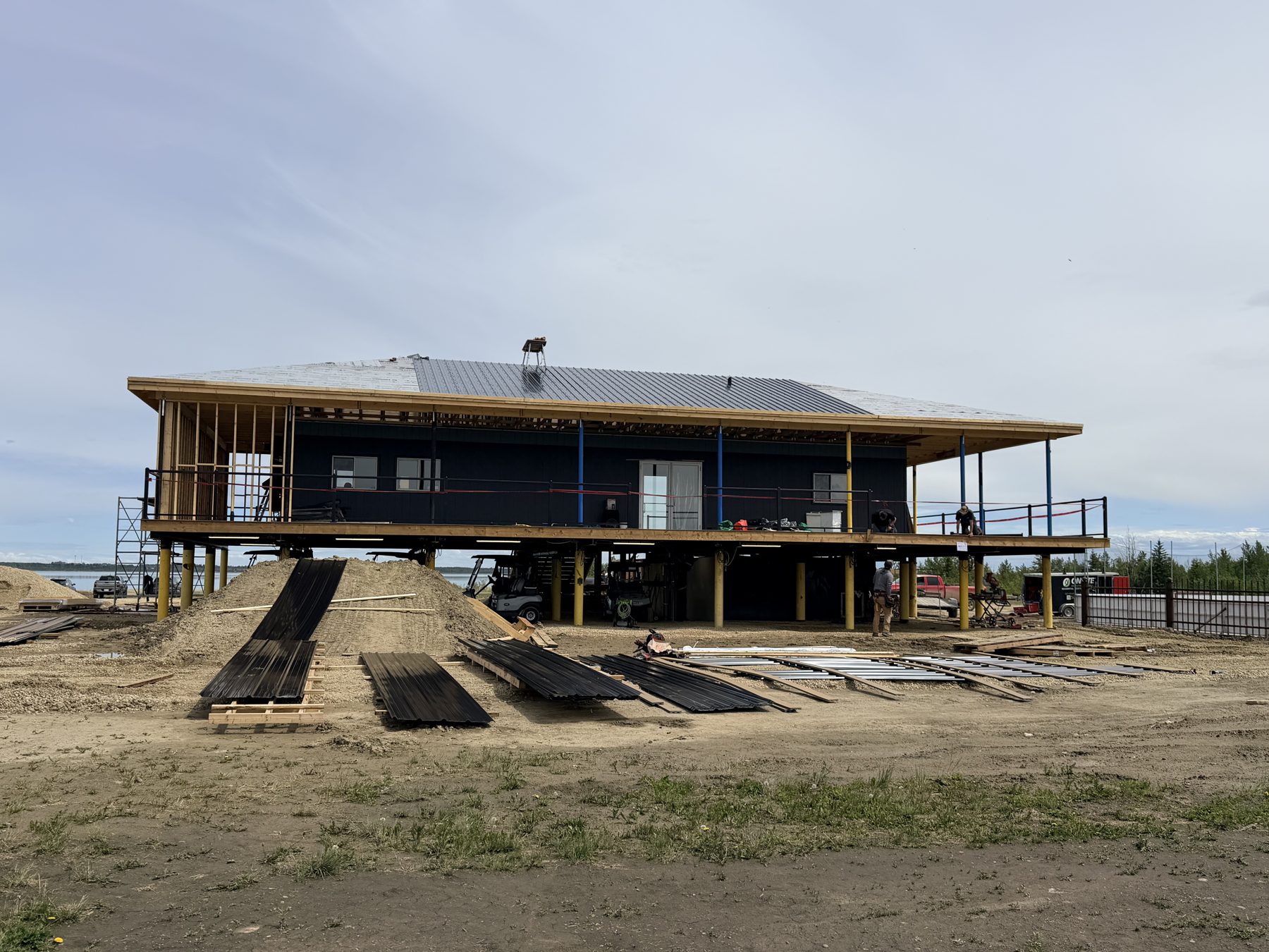 Elevated building under construction with dark siding and solar panels on roof — Sandy Point (Club House)