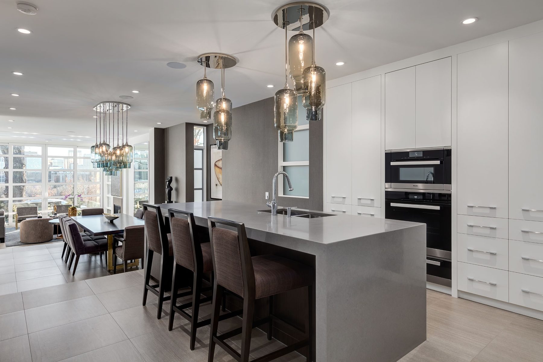 Modern kitchen with gray island, white cabinets, and pendant lights — Skyline