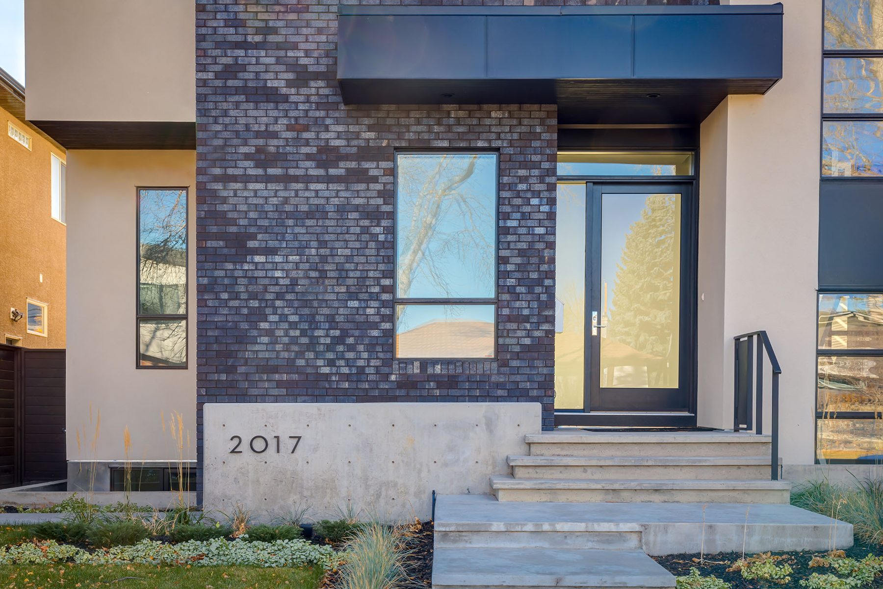Modern home exterior with dark brick, concrete, and glass entrance — Casa Blanca