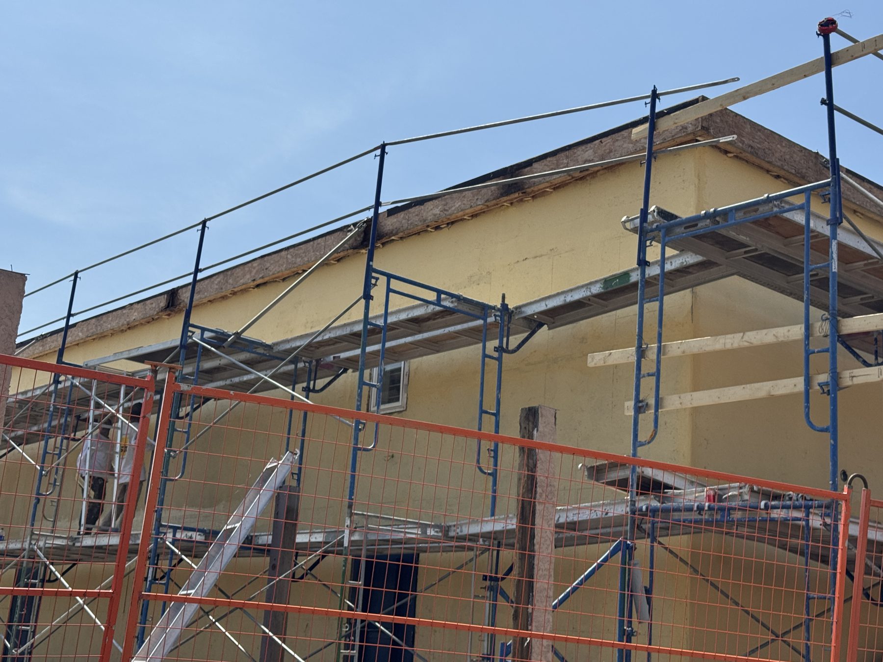 Scaffolding surrounds a building under exterior renovation with visible wood structures — Blowers and Grafton (Red Deer)