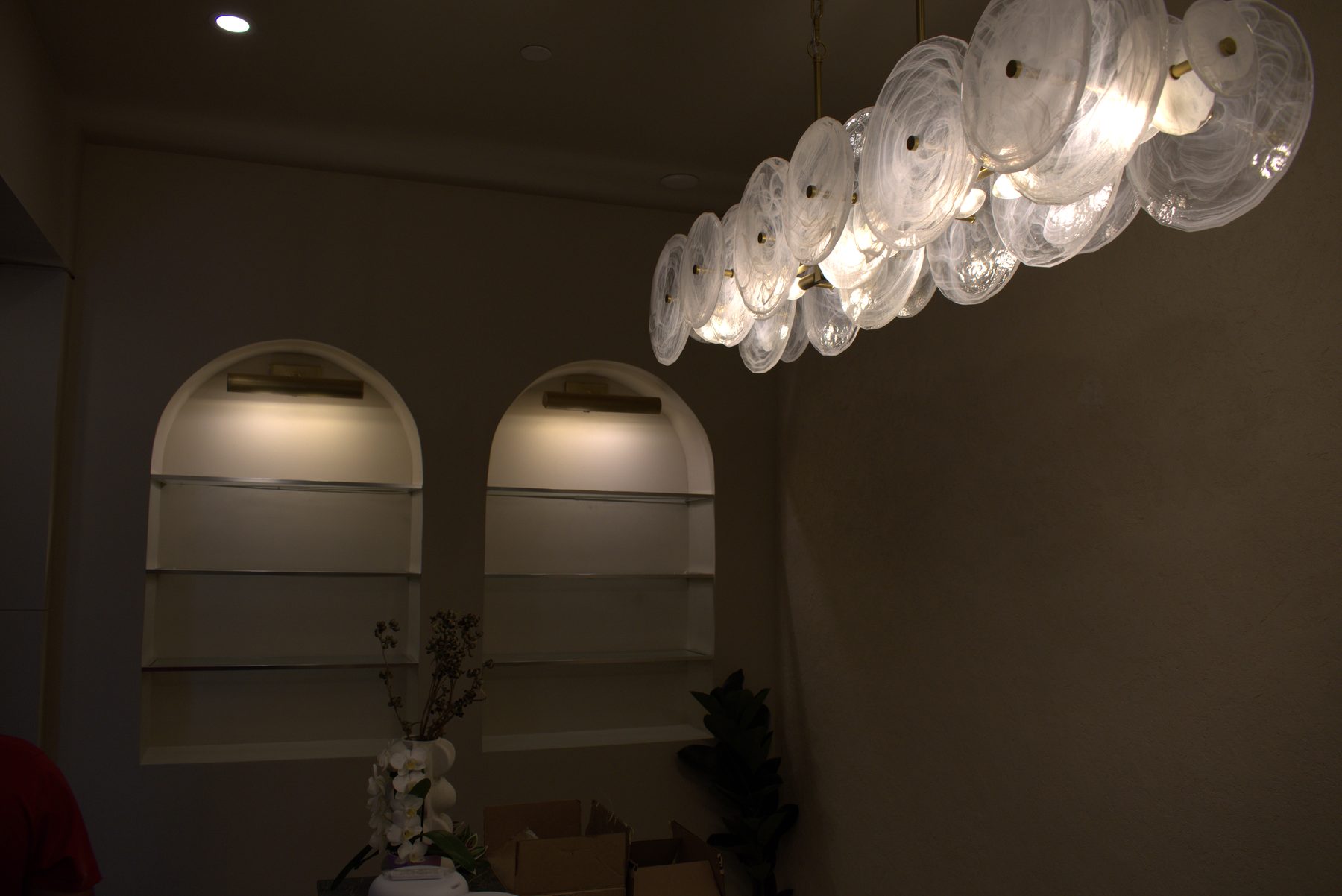 Arched alcoves with glass shelves, decorative chandelier, and floral arrangement — Leela Spa (Bankers Hall)