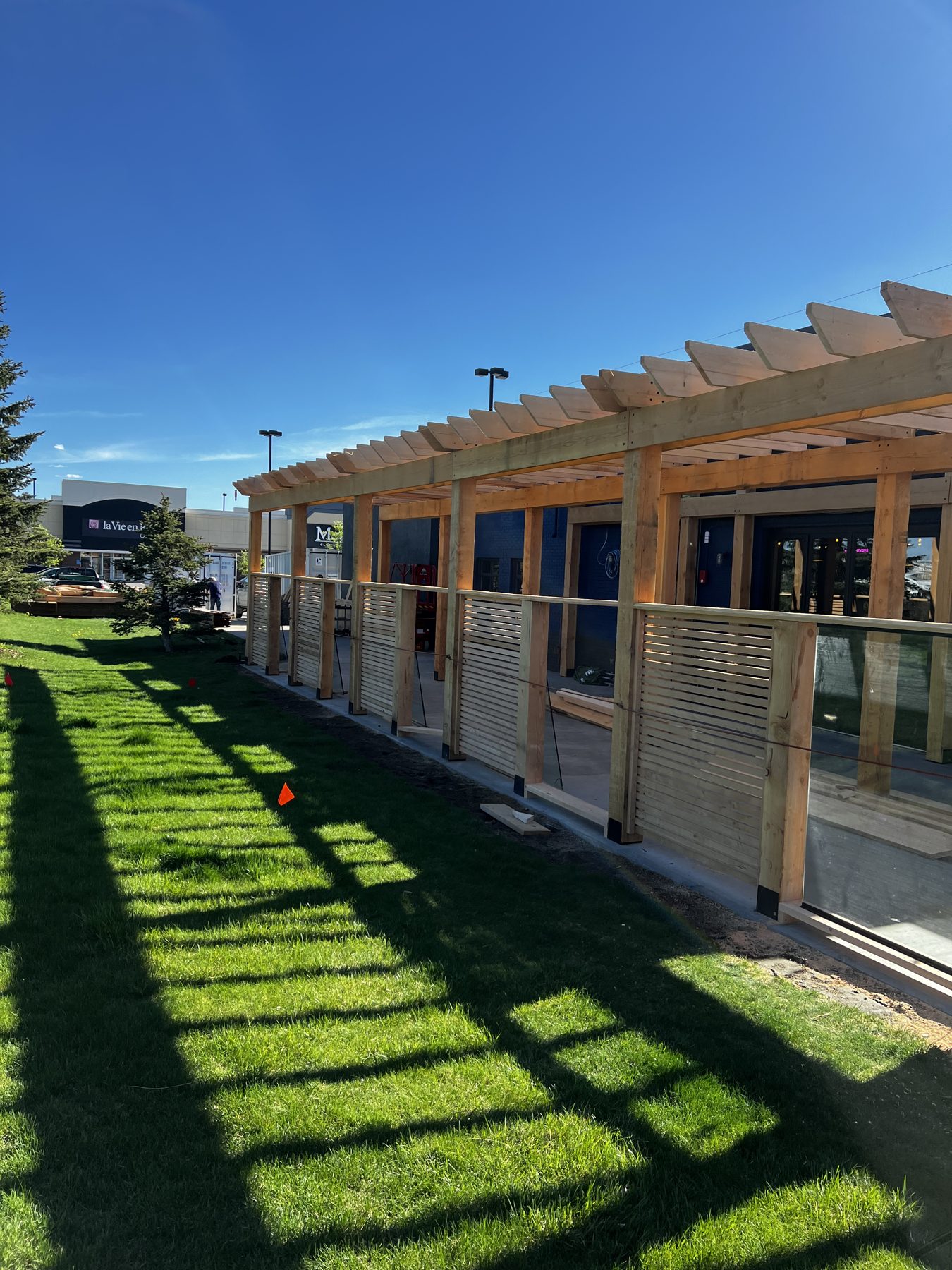 Wooden pergola construction with slatted wood screens and glass railings — Blowers and Grafton (Lethbridge)