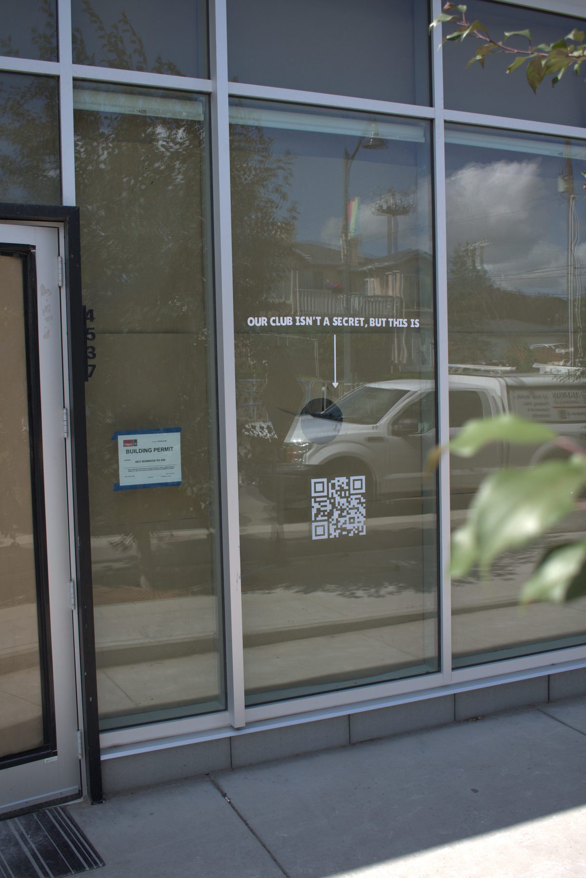 Building permit posted on glass storefront, white truck visible — Big Buns (Bowness) by Onsite Contracting Services