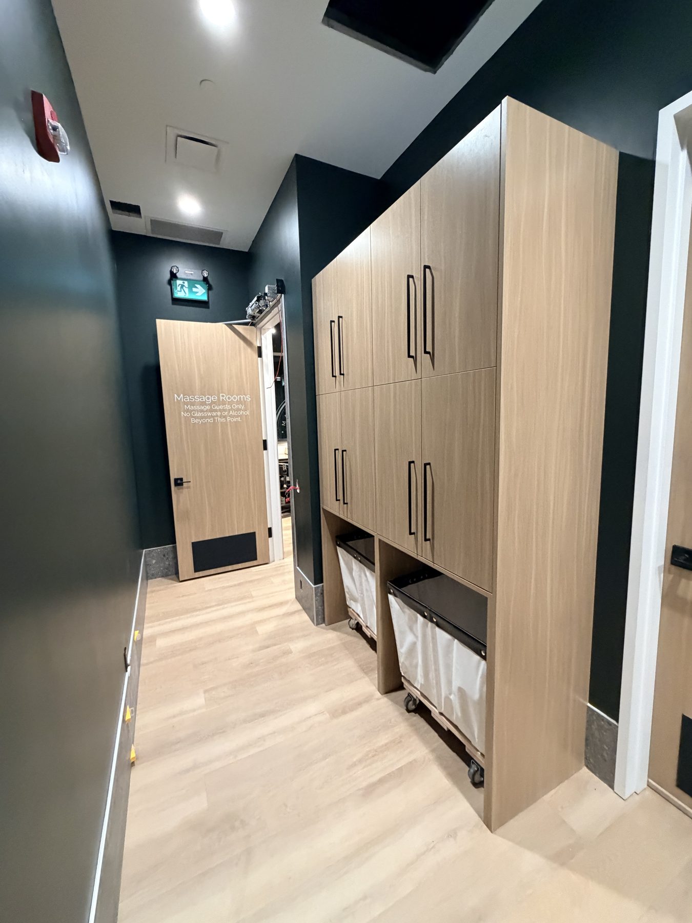 Hallway with light wood floor, dark walls, and tall cabinets — Cedar Steam and Spa (Trinity Hills)