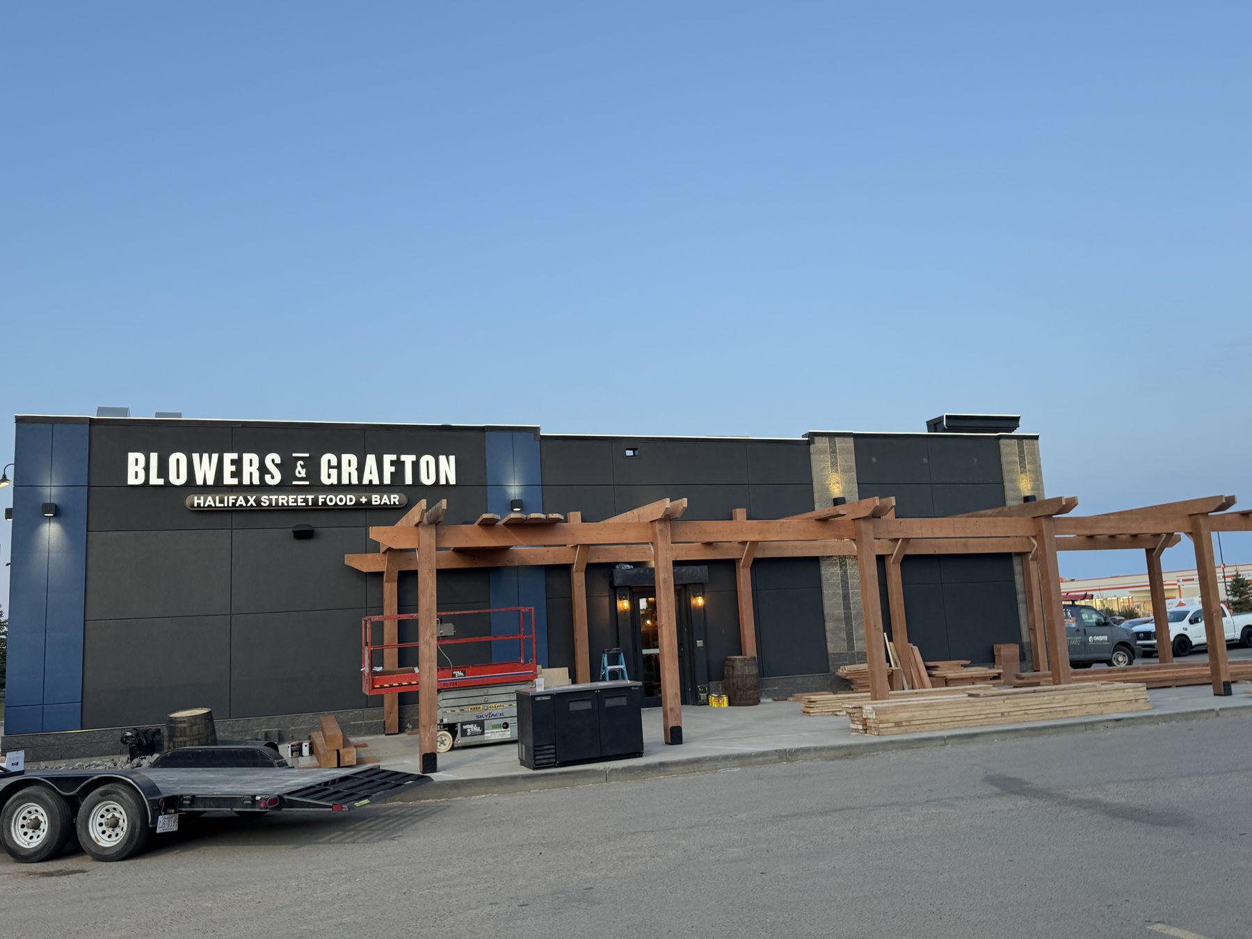 New building exterior with wood pergola construction, scaffolding and materials — Blowers and Grafton (Lloydminster)