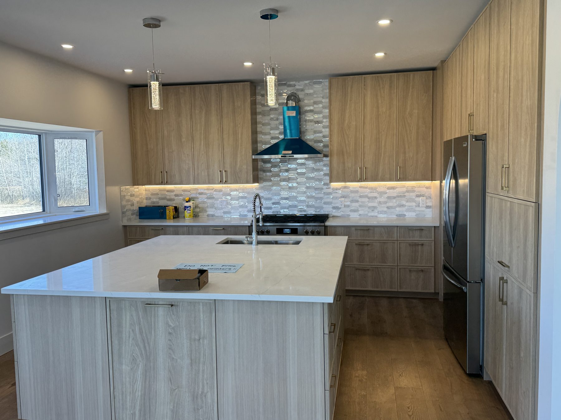 Modern kitchen island with quartz countertop, modern cabinets, and stainless steel appliances — 14 Lochend Drive, Cochrane