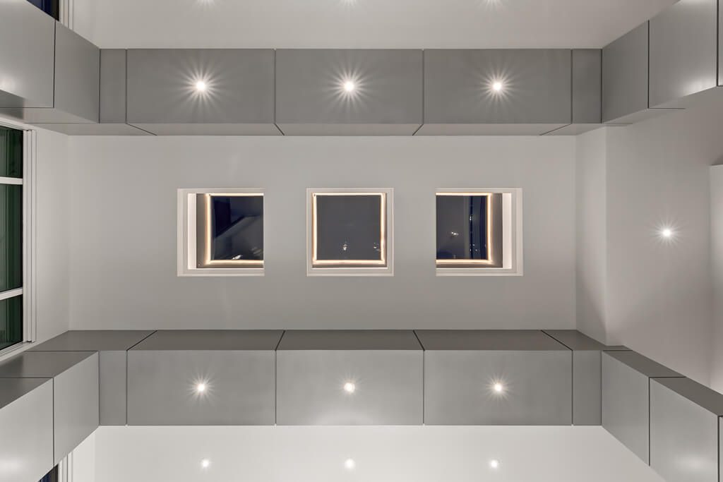 Modern renovation with recessed lighting, minimalist grey cabinets, and square windows — Blanc de Blanc