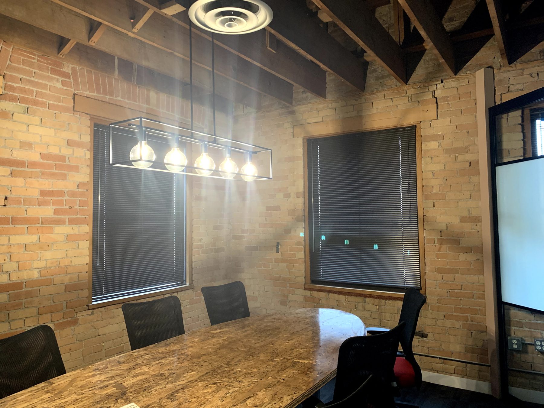 Boardroom with exposed brick, unfinished ceiling, and modern light fixture — Clearmotive (Victoria Park)