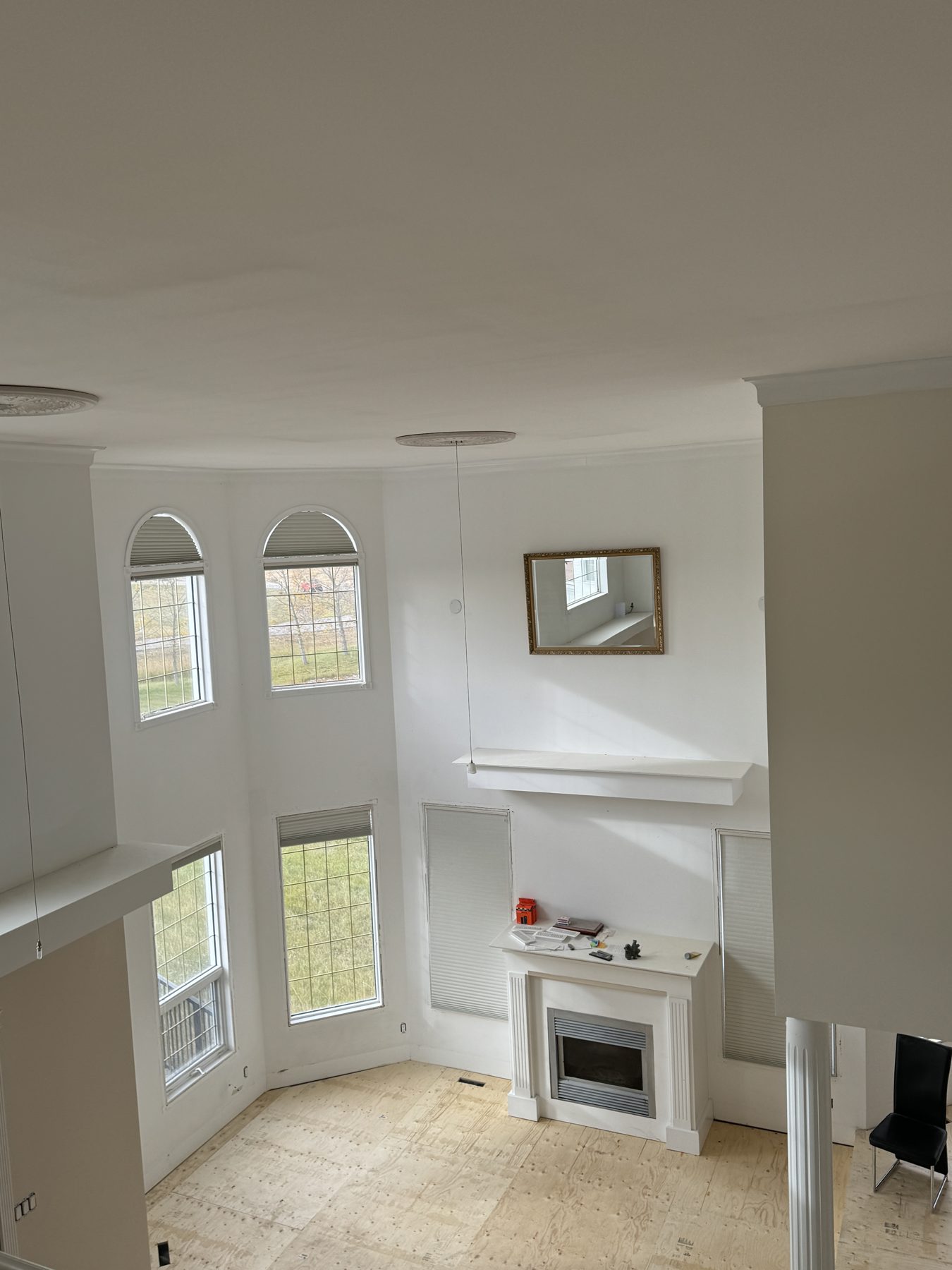 Living room under renovation with unfinished plywood floor and white fireplace — 14 Lochend Drive, Cochrane