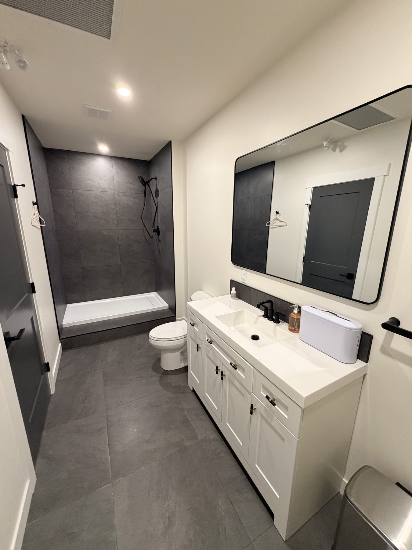 Modern bathroom renovation with grey tile shower, white vanity, and black fixtures — The Barron Venue