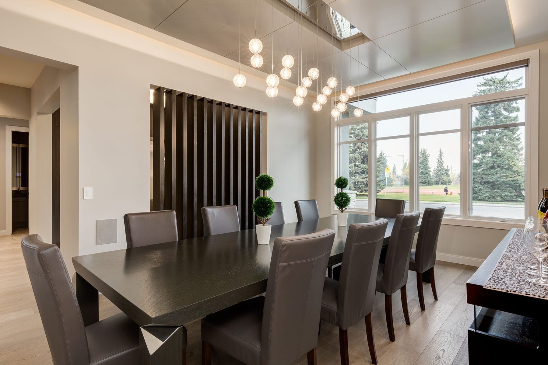 Modern dining room with dark table, grey chairs, and bubble chandelier — The Cellar