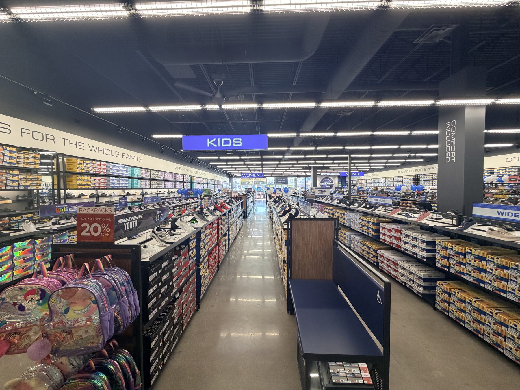 Shoe store interior with aisles of shoe boxes, backpacks, and display shelves — Skechers (Signal Hill)
