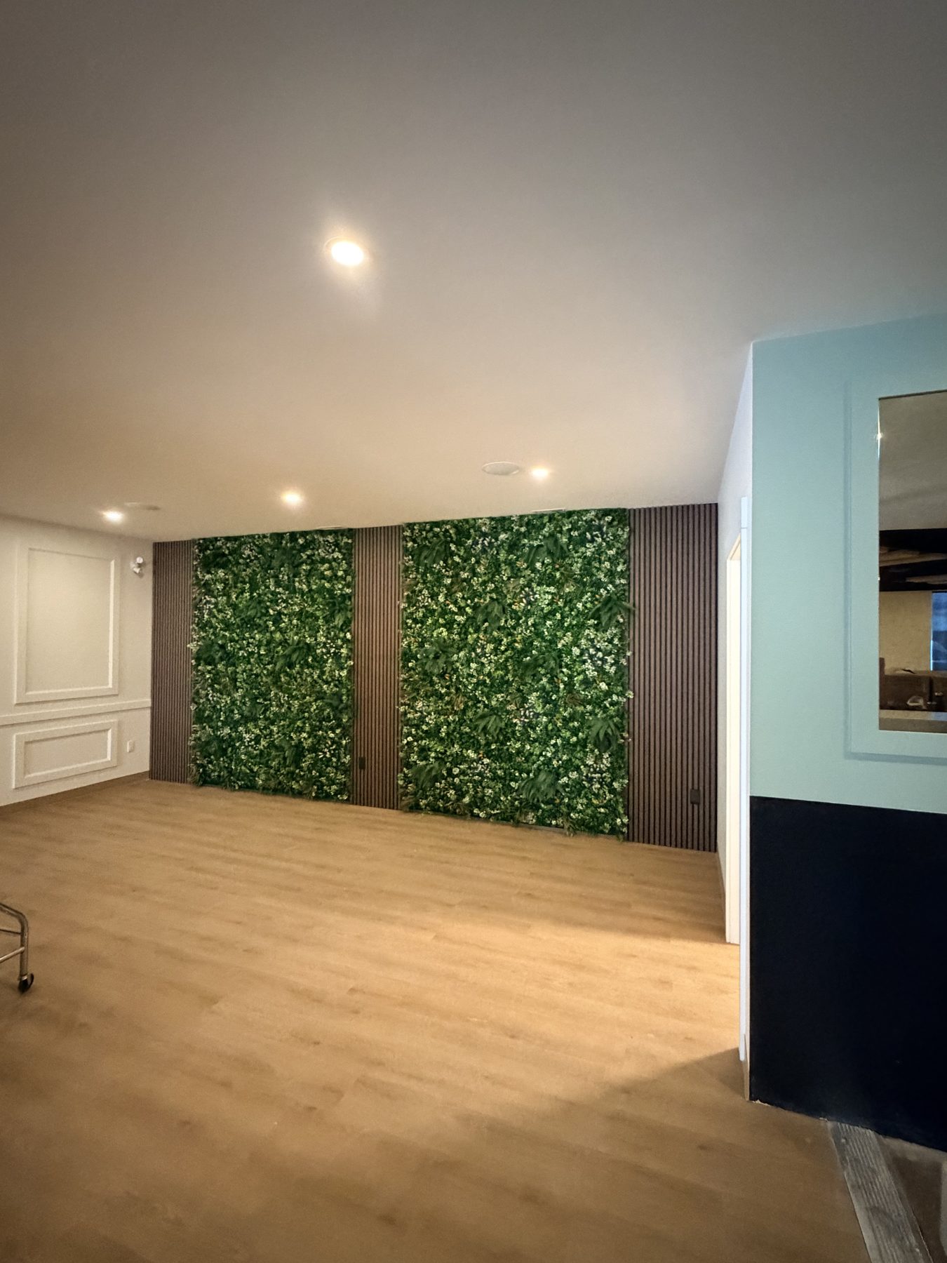 Living wall with wood panels, light wood floor, wainscoting, and ceiling lights — The Barron Venue