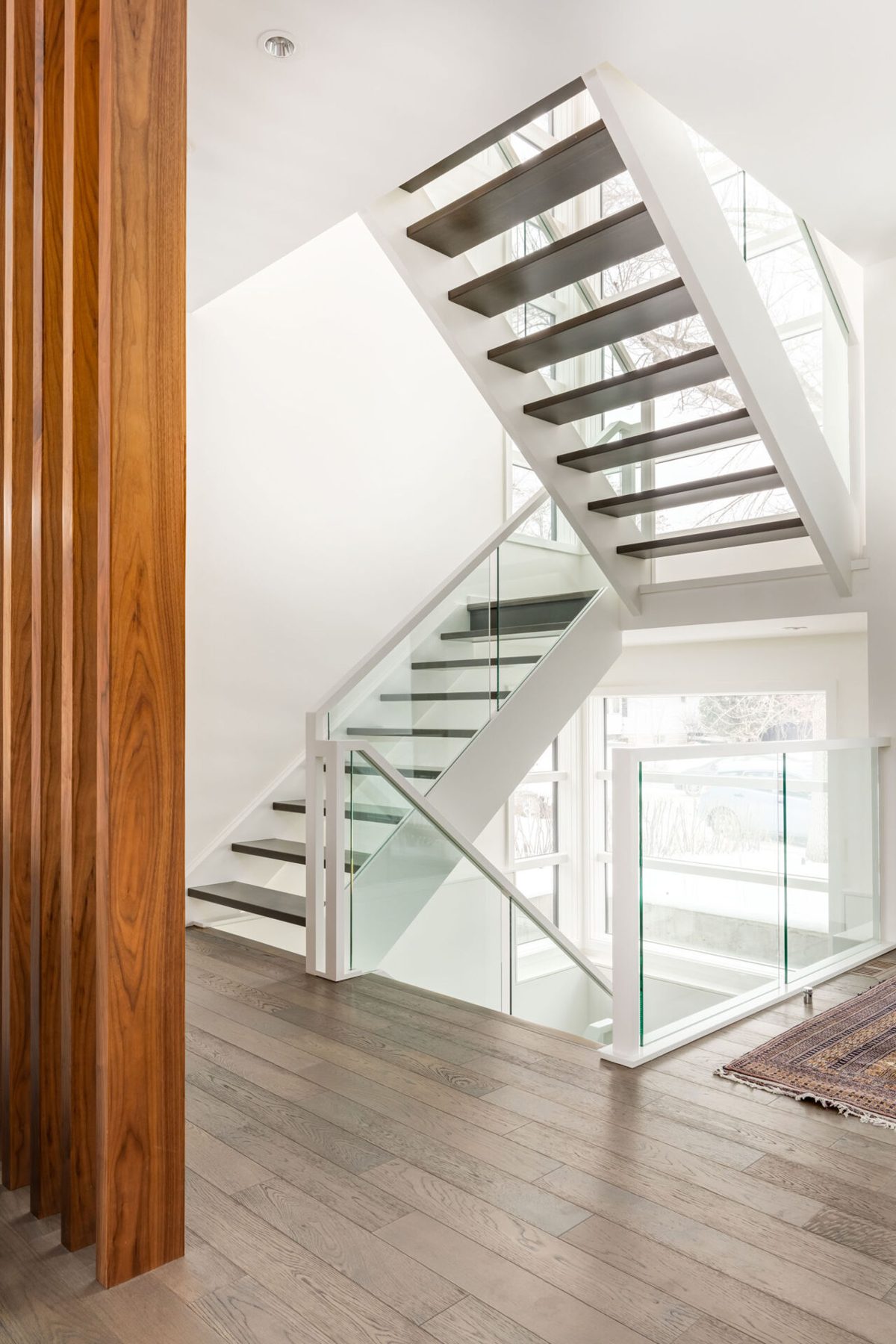 Modern floating staircase with glass railings and dark wood treads — Casa Blanca
