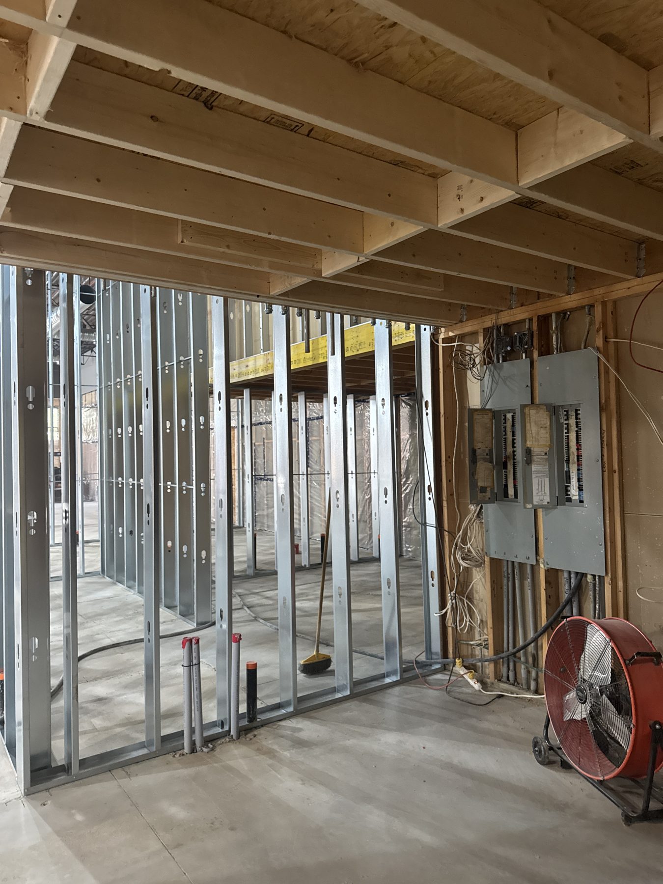 Metal stud framing, electrical panel, and a fan in unfinished room — Blowers and Grafton (Red Deer)