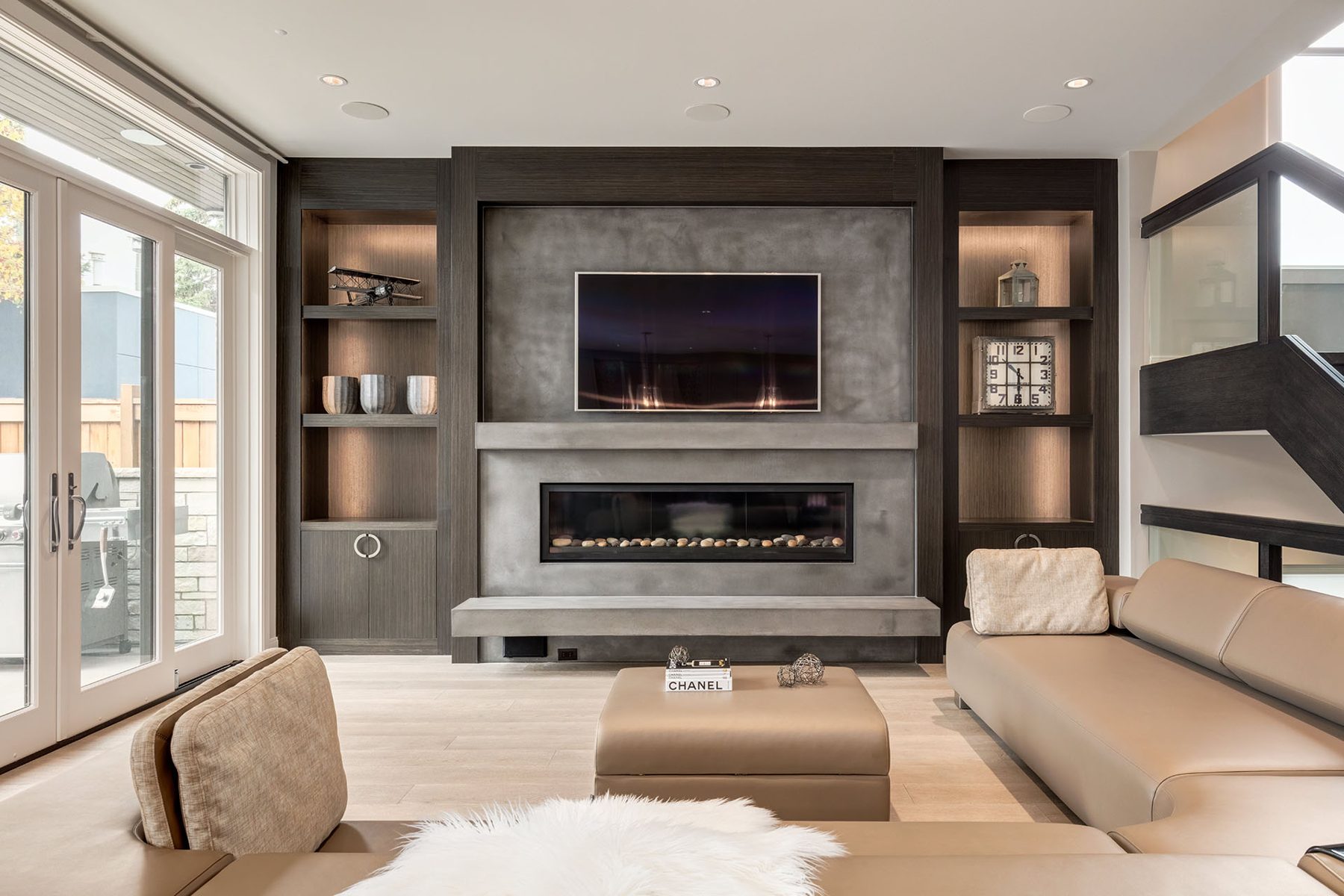 Modern living room with concrete fireplace, television, and built-in shelving — The Cellar