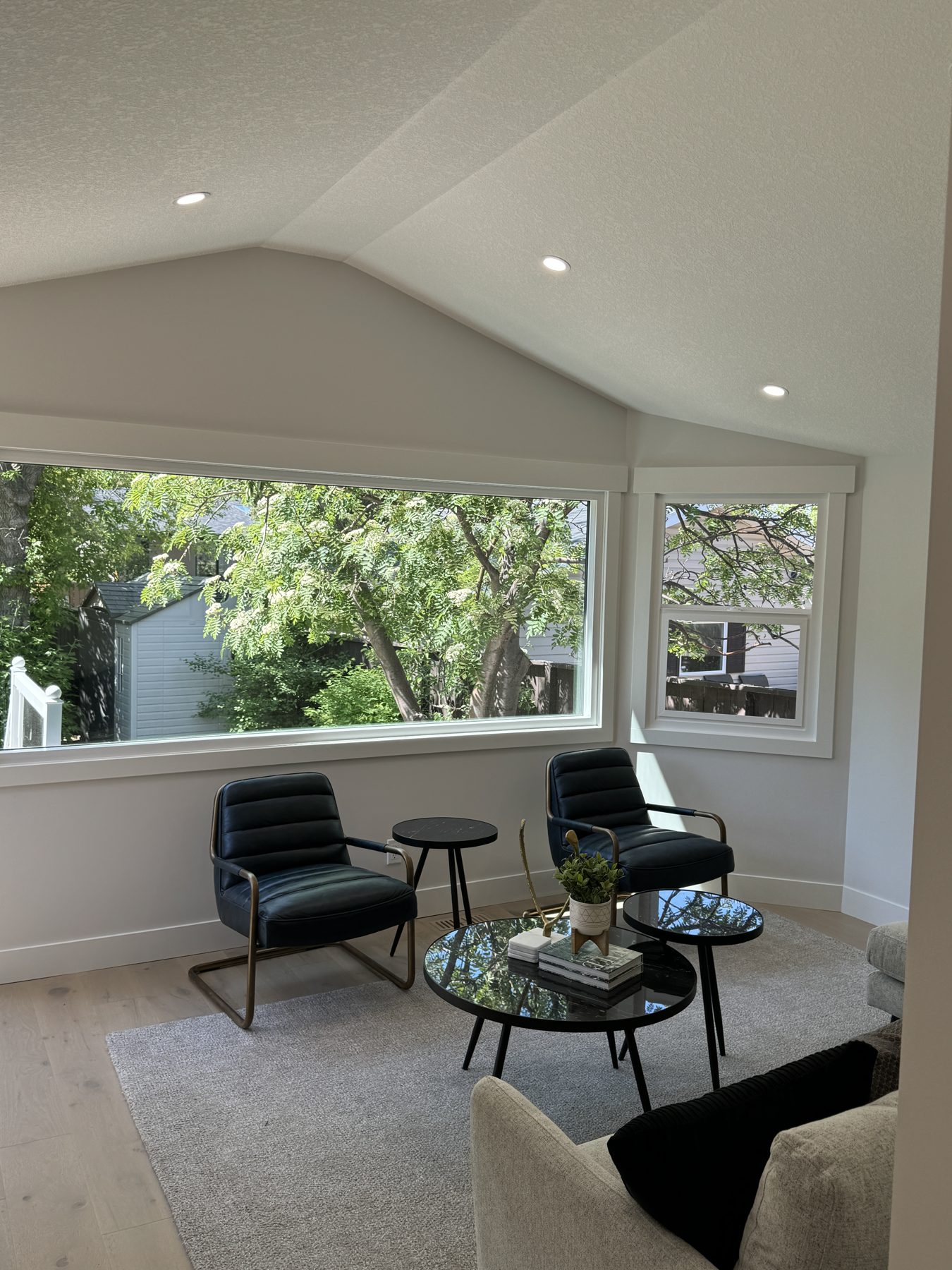 Living room with vaulted ceiling, new windows, recessed lights, and light wood floors — Lake Bonavista