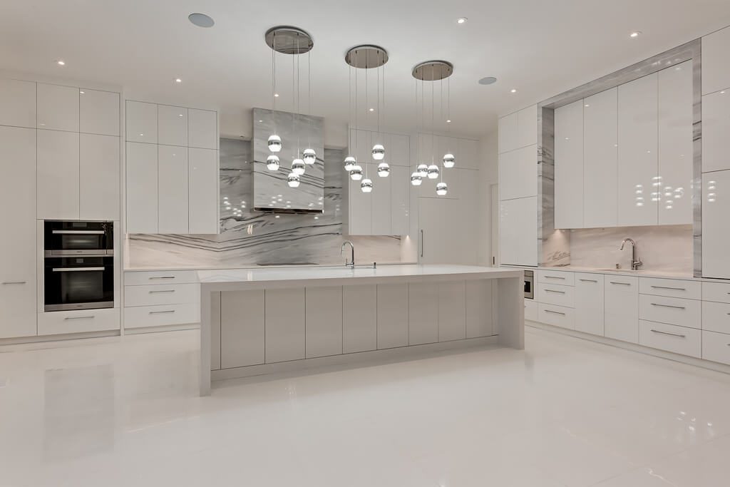 Modern white kitchen with island, contemporary pendant lights, and marble backsplash — Blanc de Blanc