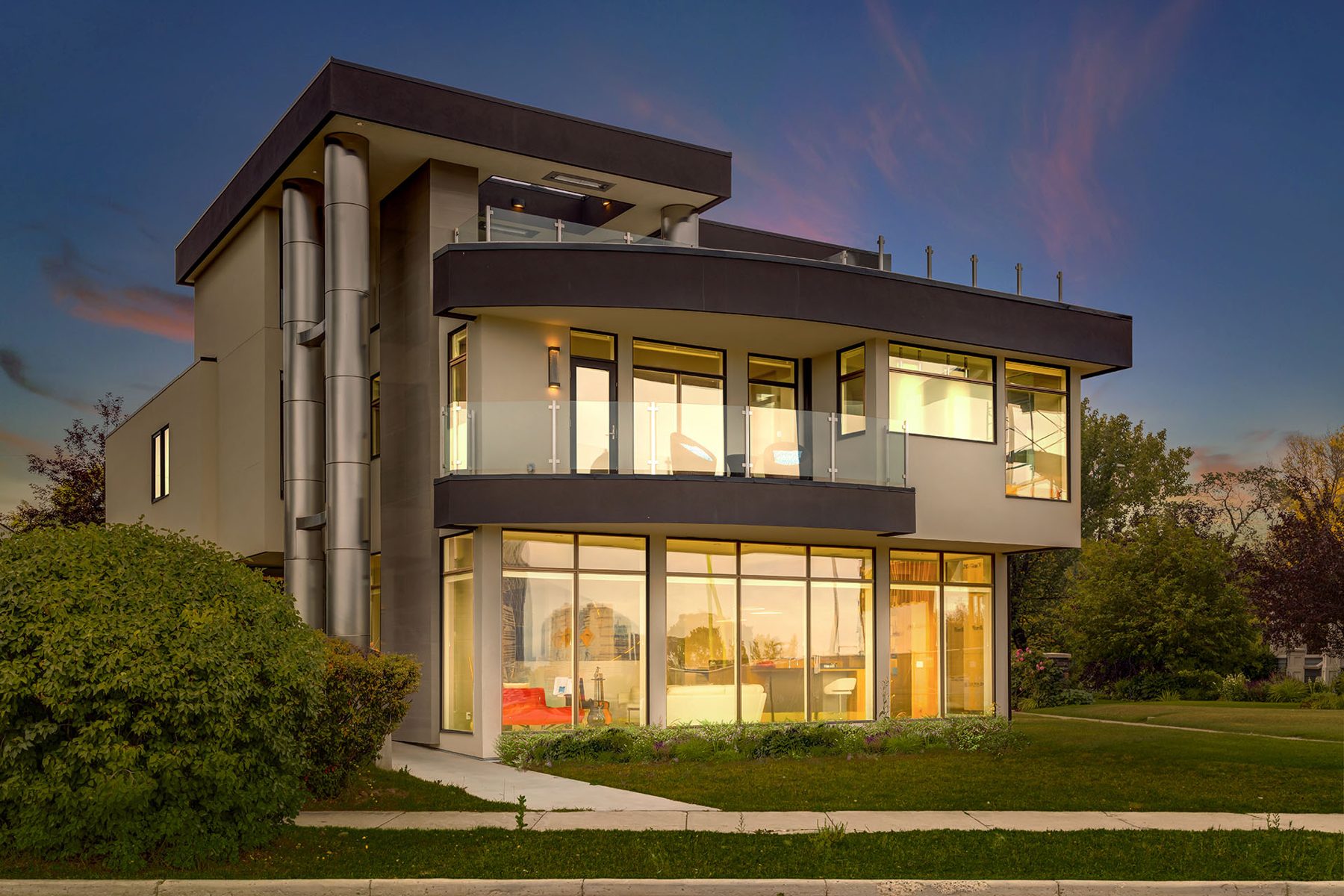 Modern house exterior with large windows, glass balconies, and metal columns — Timeless Form by Onsite Contracting Services