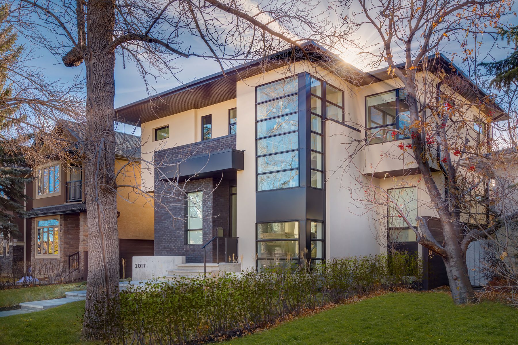 Modern home exterior with cream siding, dark windows, and brick accent — Casa Blanca by Onsite Contracting Services