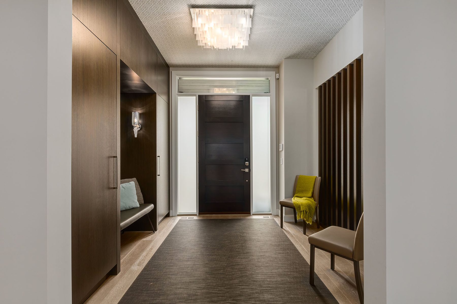 Modern entryway features dark wood closet, bench, and slatted screen — The Cellar