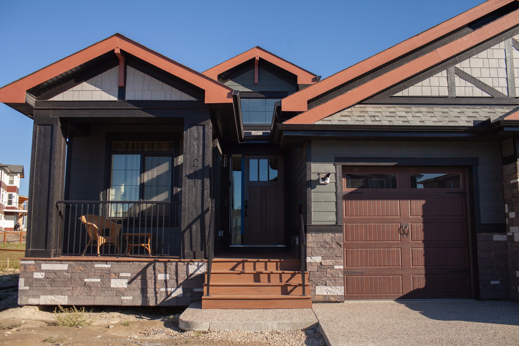 Exterior of a house under construction with dark siding and stone — 211 Blackstone Rd