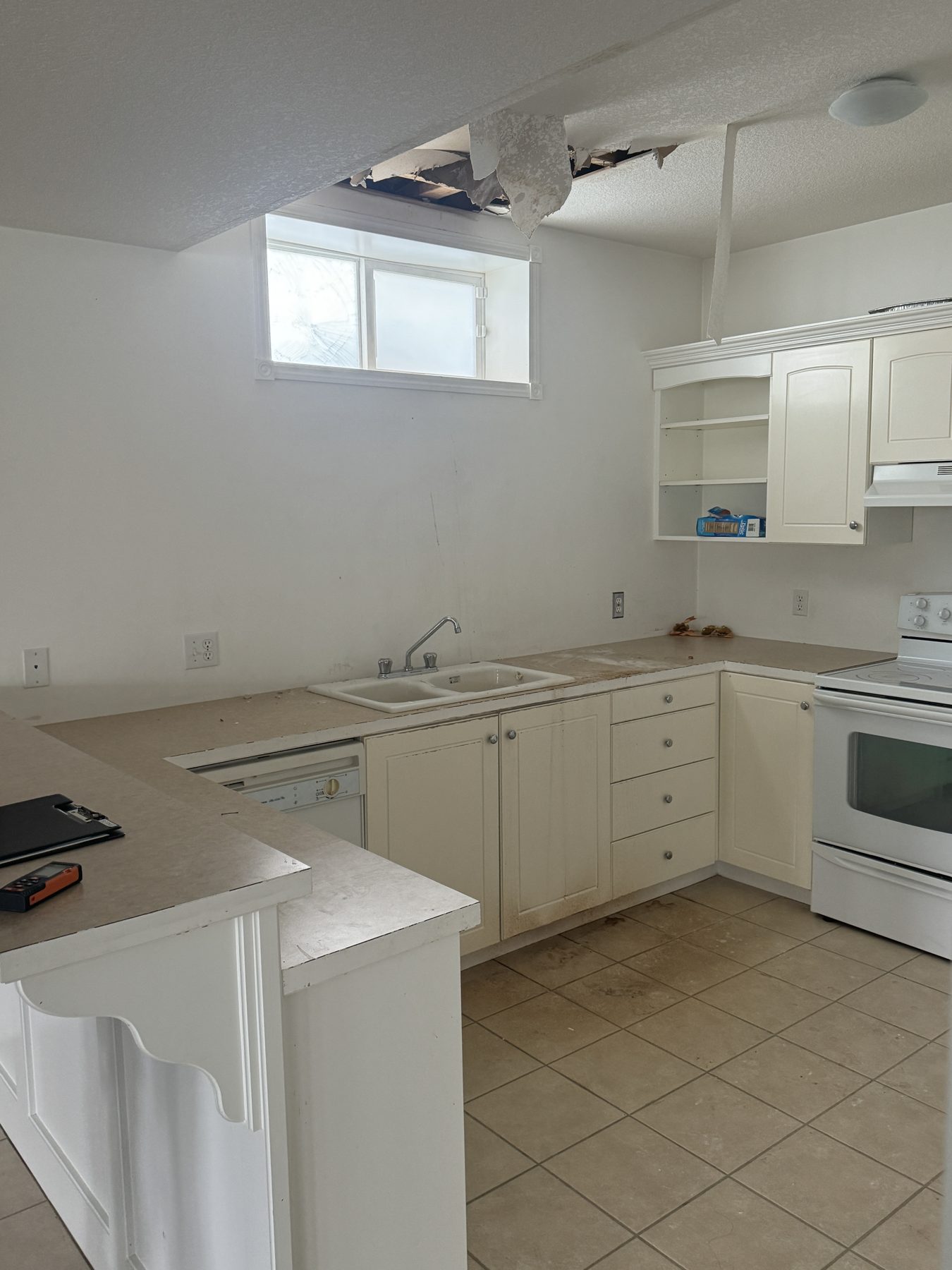 Kitchen renovation with damaged ceiling, cabinets, sink, and appliances — 14 Lochend Drive, Cochrane