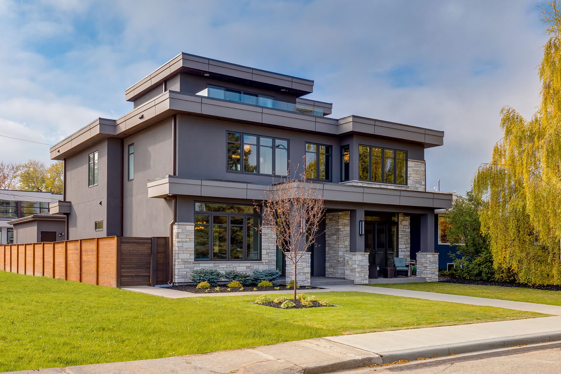 Modern house with gray siding, stone accents, and large windows — The Cellar