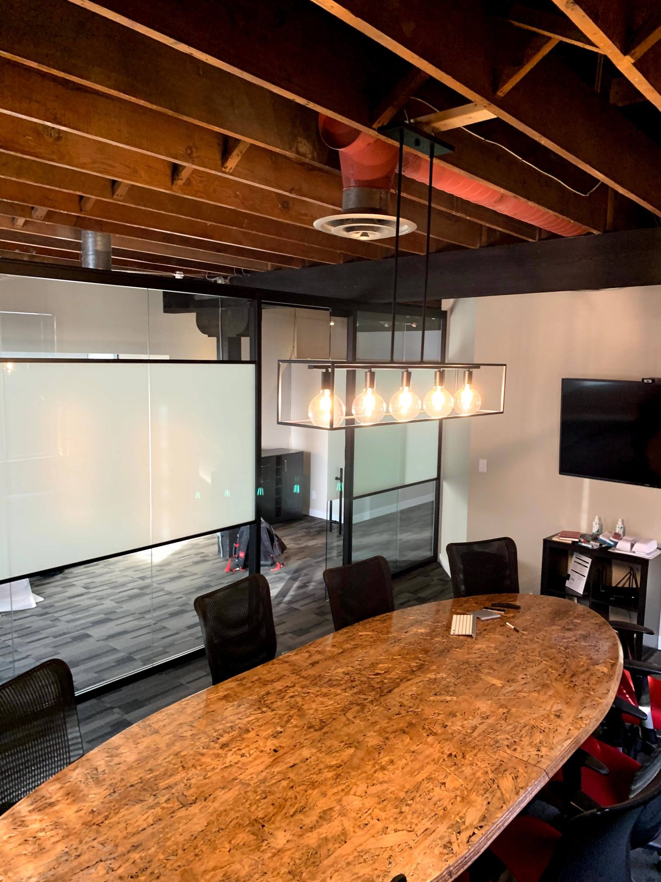 Conference room with unfinished wood ceiling, glass walls, and oval table — Clearmotive (Victoria Park)