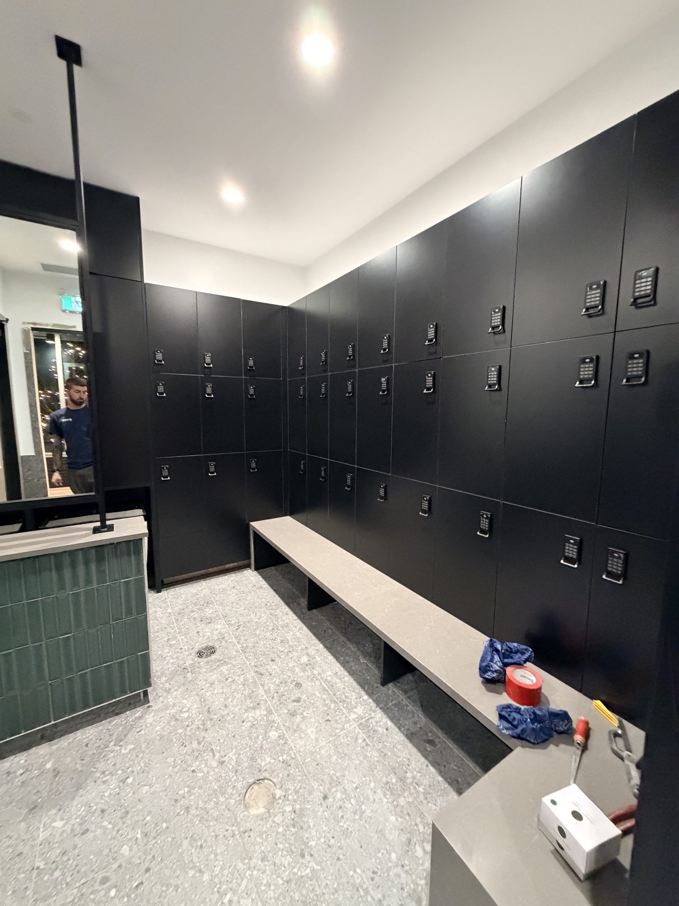 Black lockers with digital locks, stone bench, terrazzo floor, ongoing work — Cedar Steam and Spa (Trinity Hills)