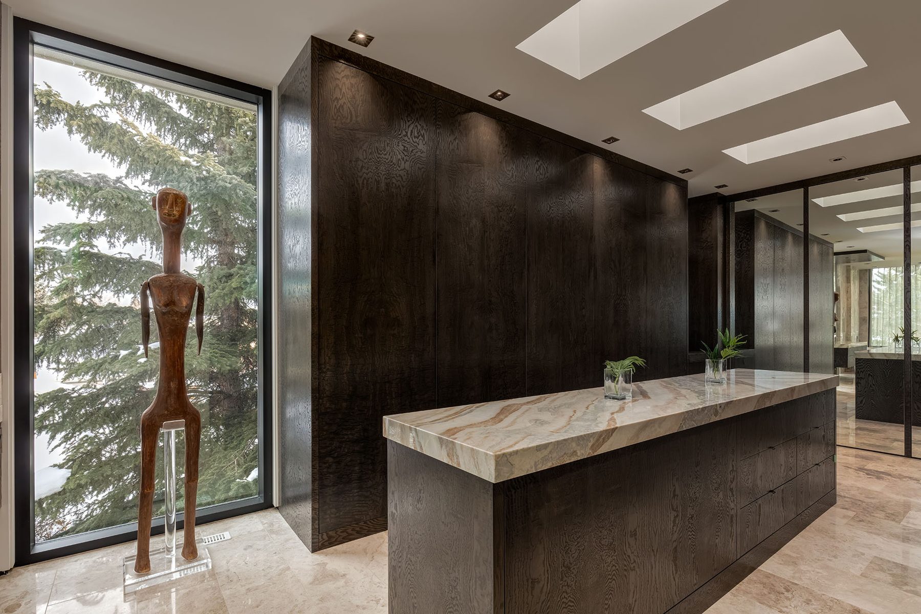 Dark wood cabinets with marble countertop, large window, sculpture, skylights — Modern Family
