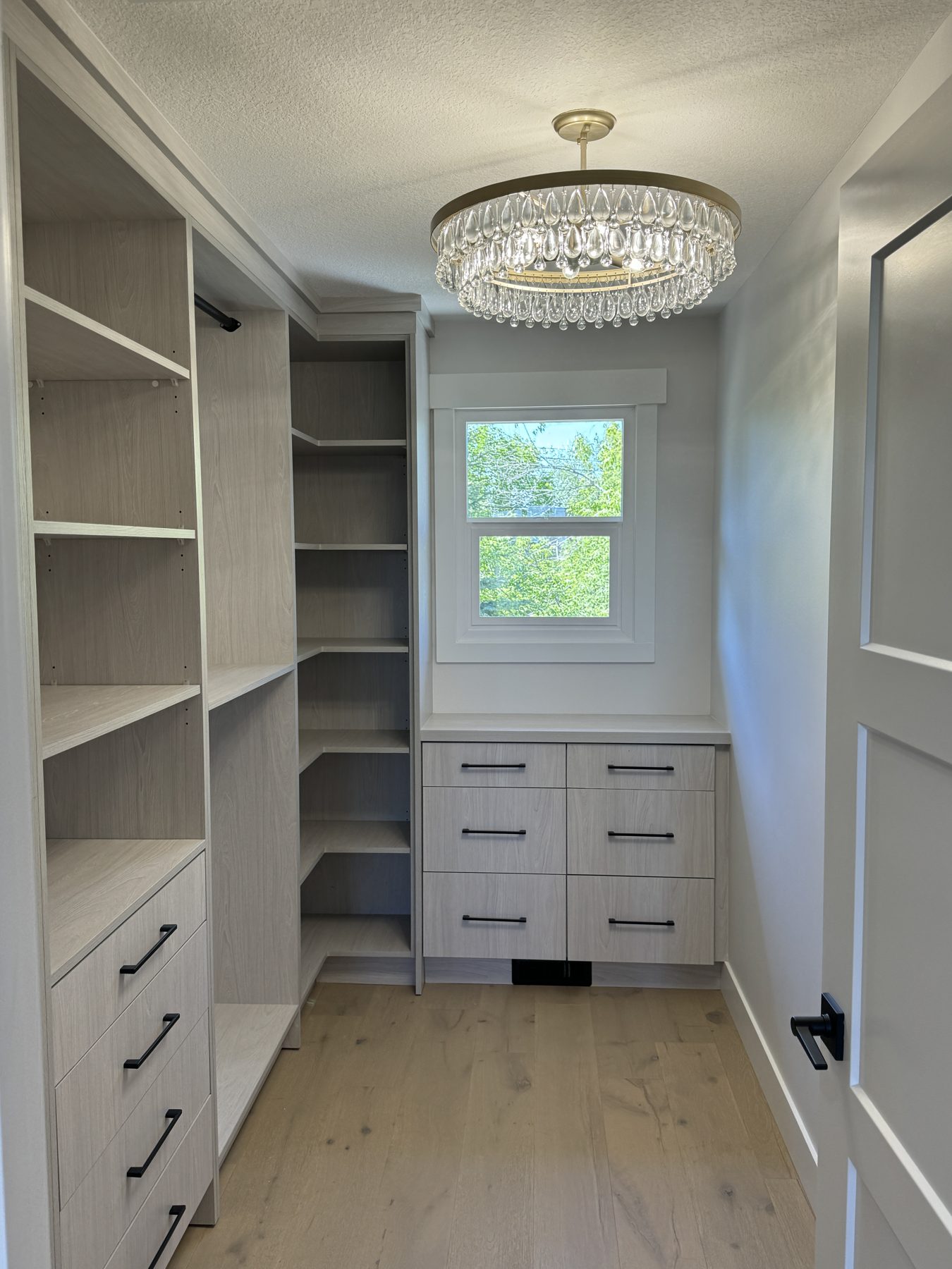 Closet renovation with blonde wood cabinets, drawers, and crystal chandelier — Lake Bonavista