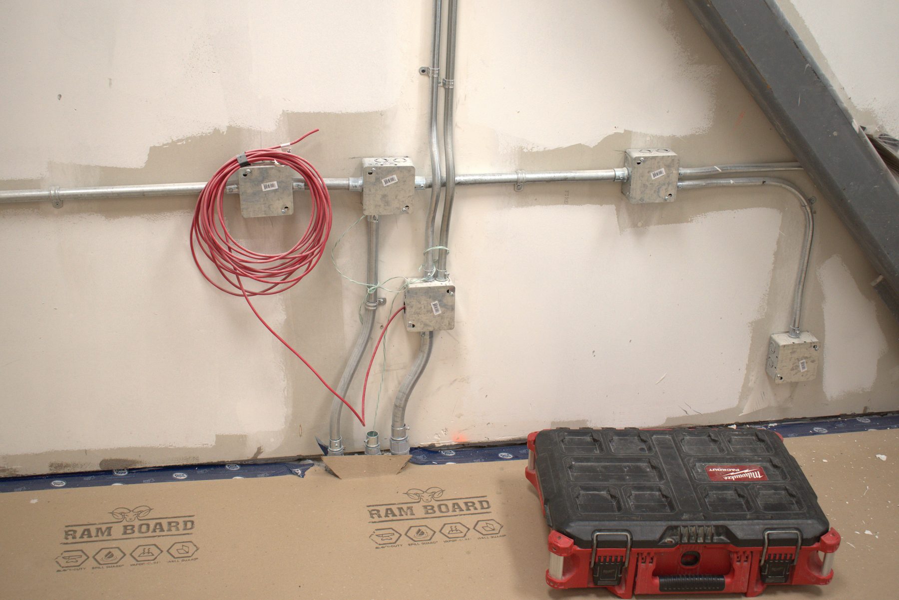 Electrical conduit and boxes on unfinished wall, with tools nearby — ONE8T (West District)