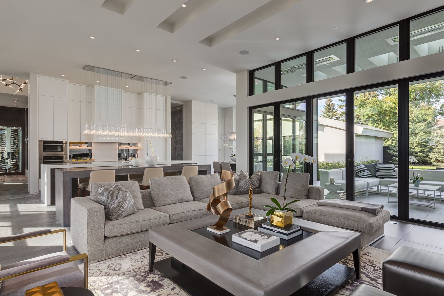 Modern living room and kitchen with gray sectional and glass doors — Infinity