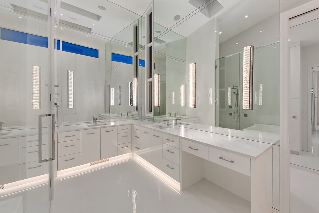 Modern bathroom renovation with white cabinets, marble counters, and large mirrors — Blanc de Blanc