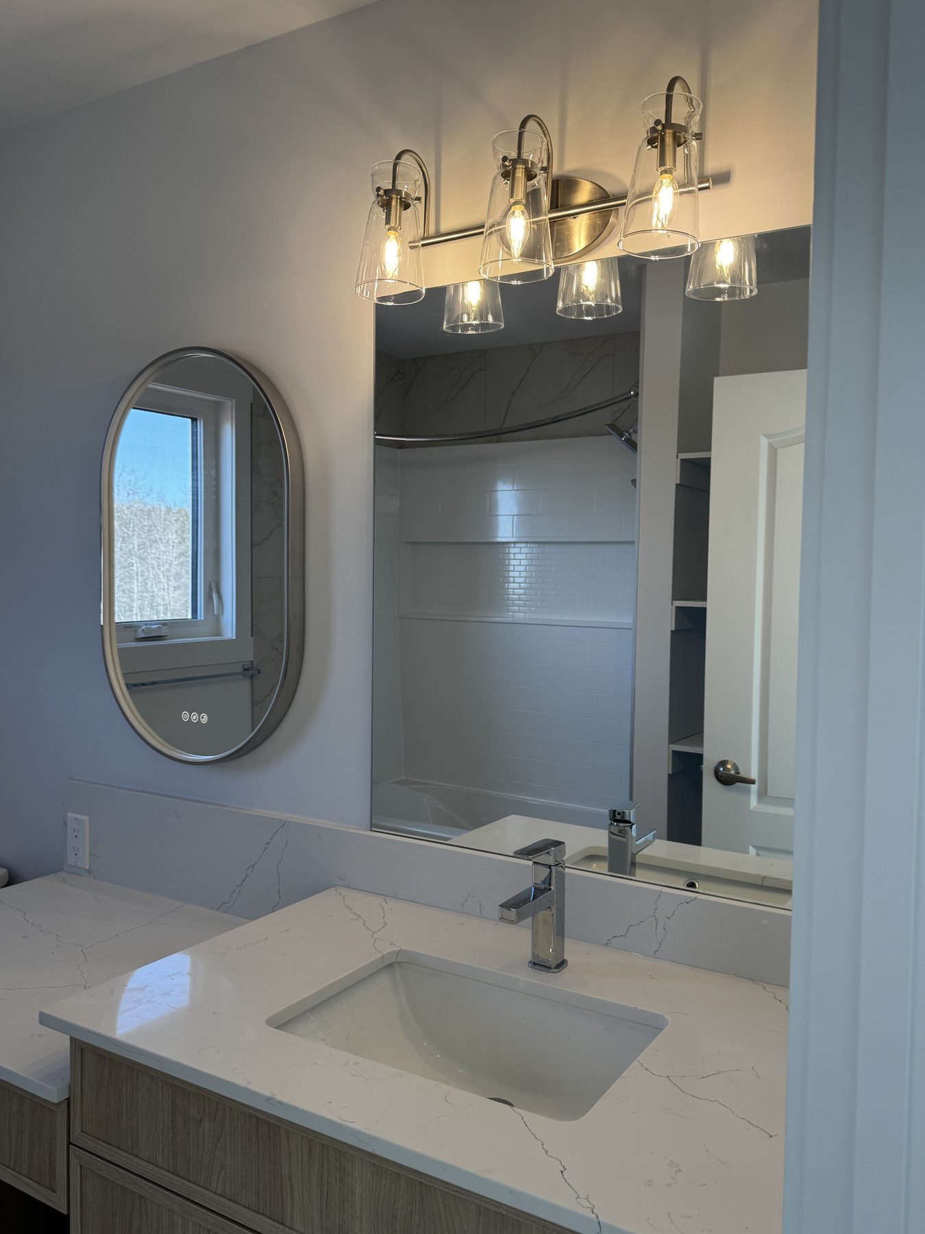 Newly renovated bathroom with vanity, sink, oval mirror, and shower — 14 Lochend Drive, Cochrane