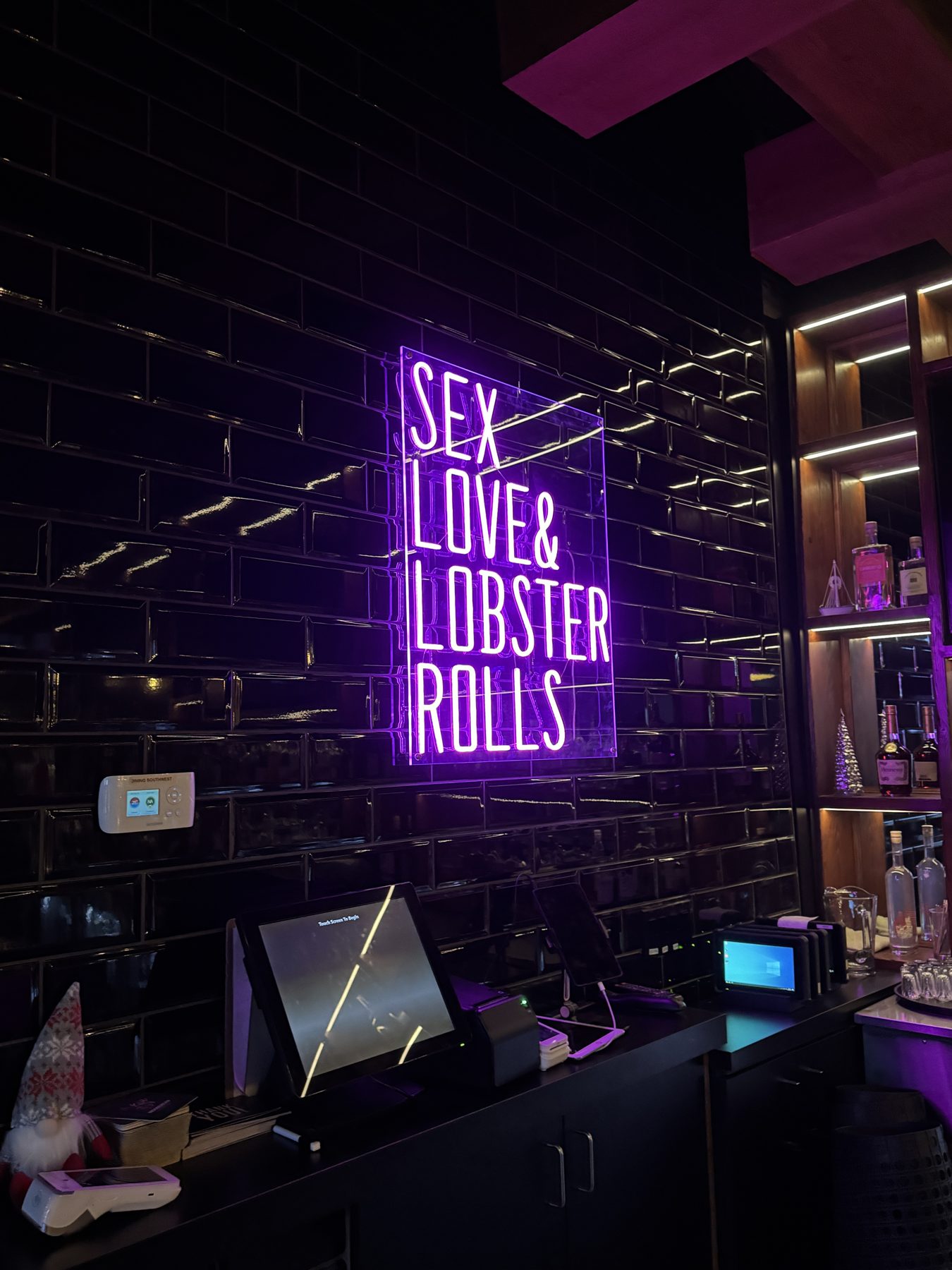 Black tiled wall with purple neon sign and checkout counter — Blowers and Grafton (Mission)