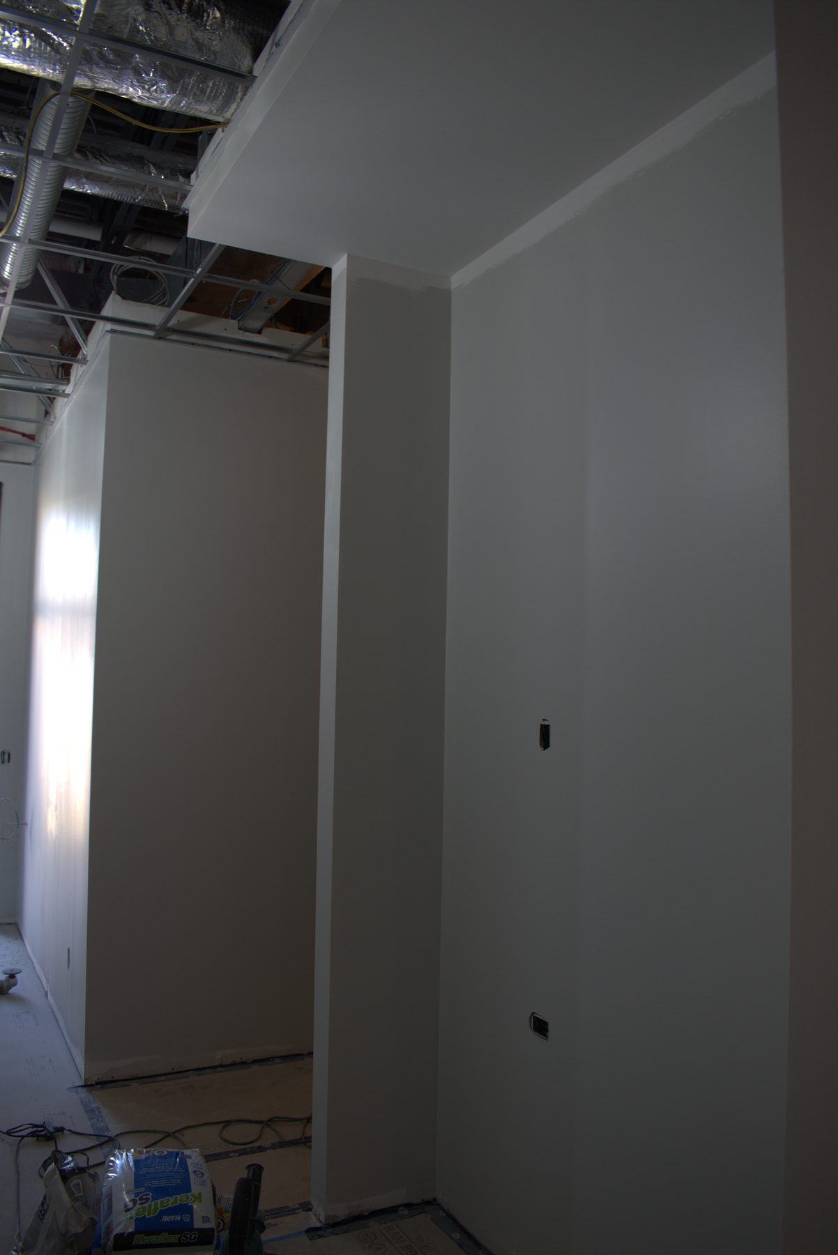 Newly painted walls, exposed ceiling infrastructure, and construction materials on the floor — ONE8T (West District)