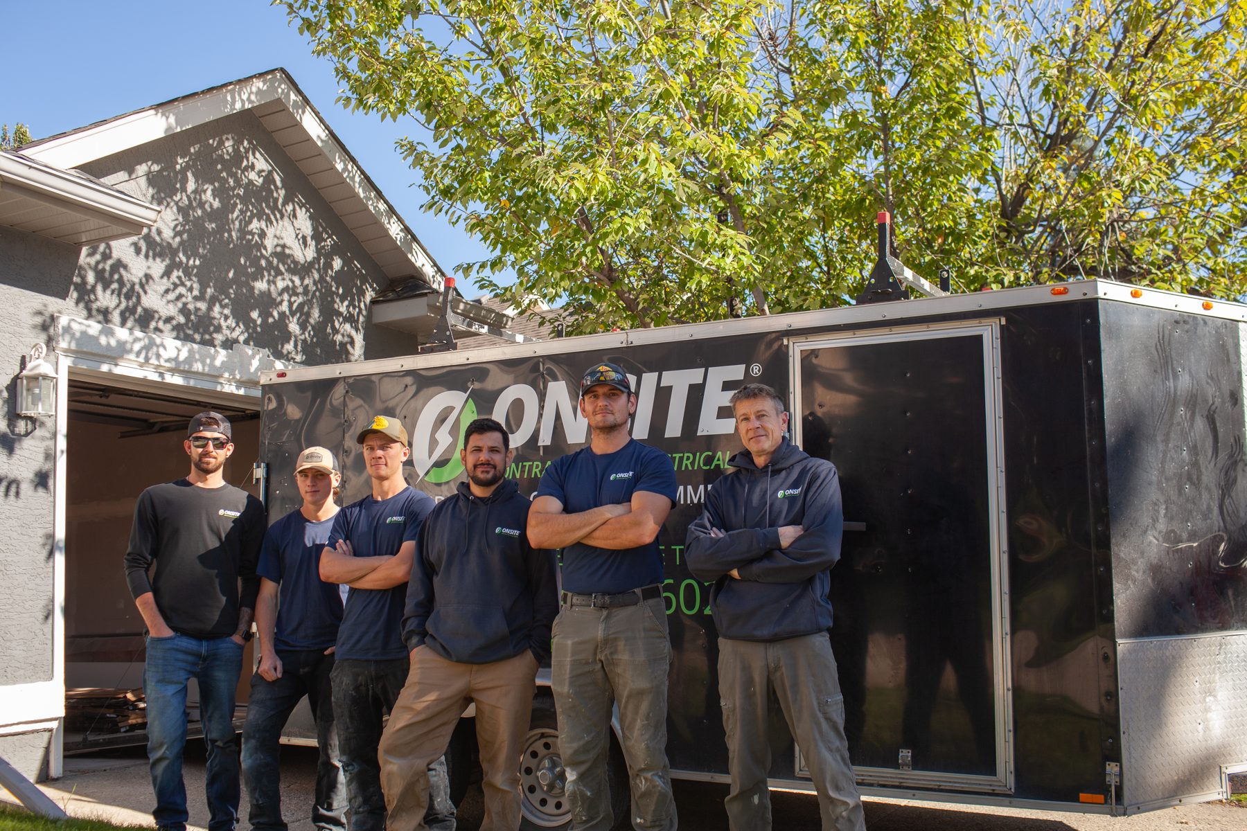 Construction crew stands by trailer at house with open garage door — 32 Somercrest Manor SW