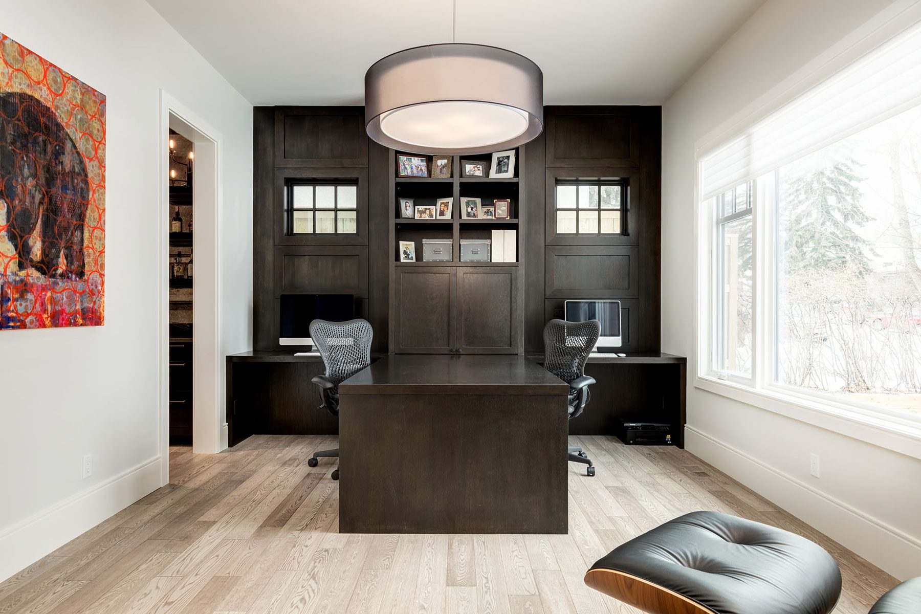 Modern office with dark wood built-ins, two workstations, and natural light — Cleret Velour