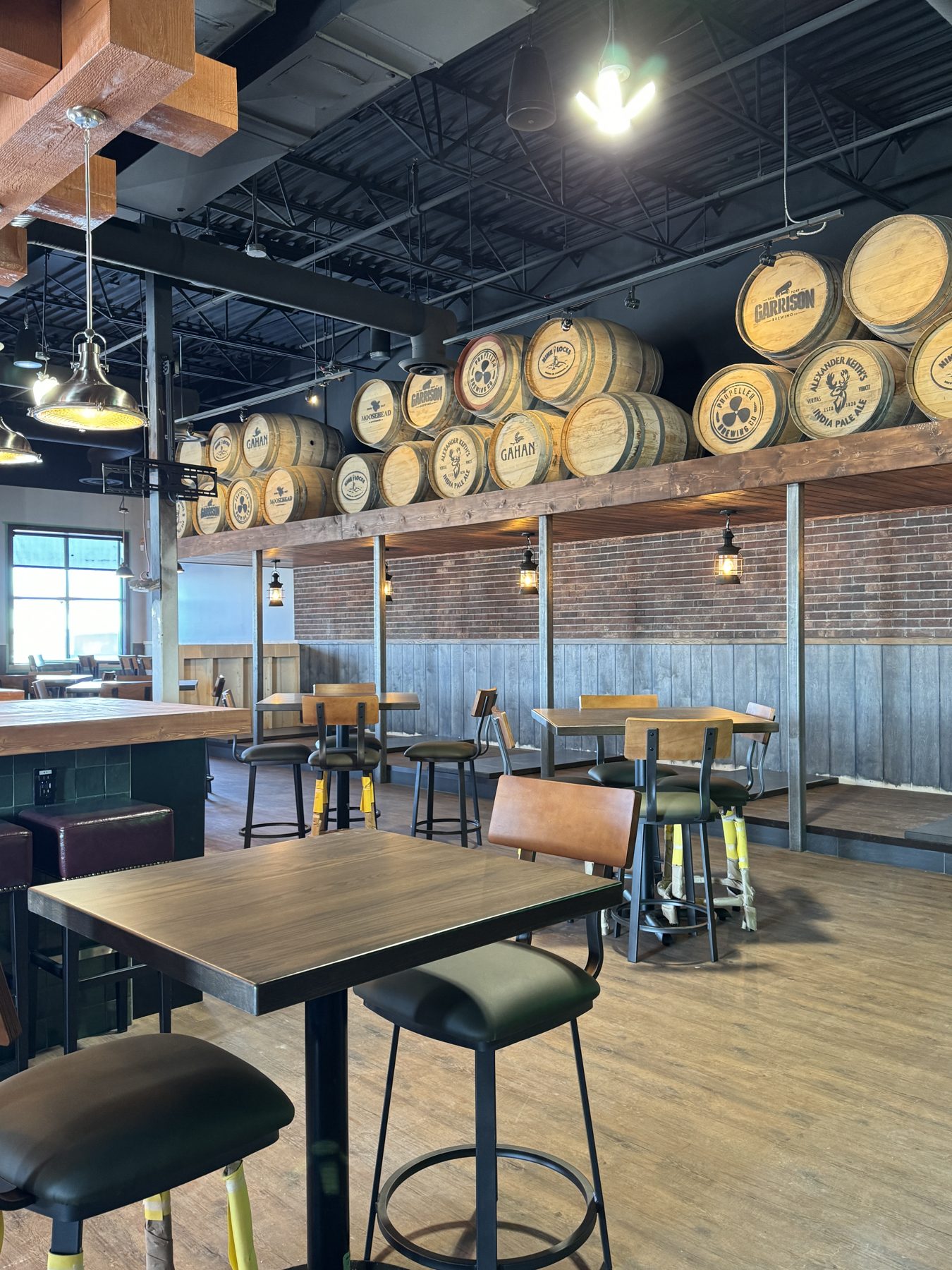 Brewery interior with stacked barrels, tables, and bar seating — Blowers and Grafton (Medicine Hat)