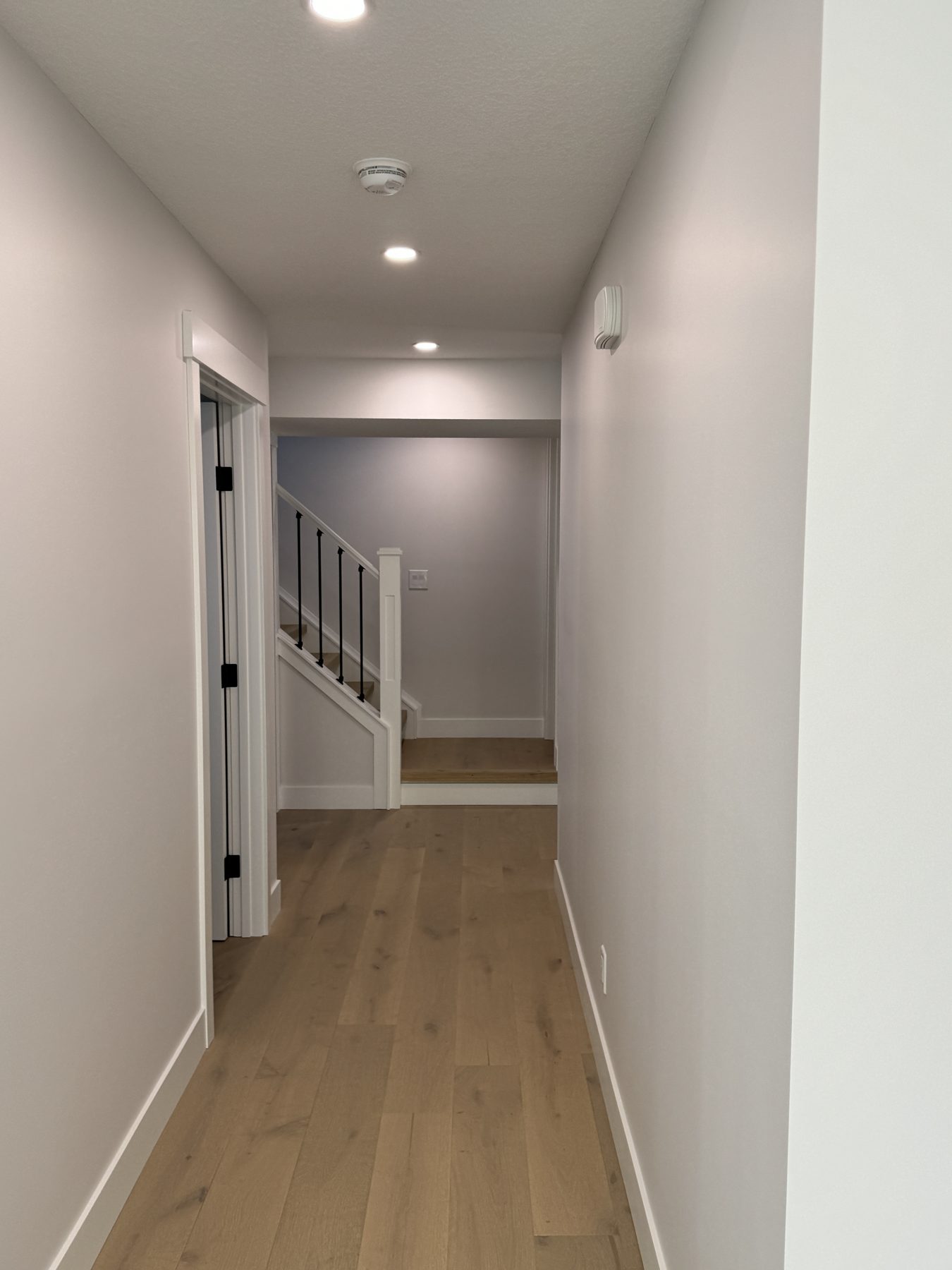 Hallway with new hardwood floors, white trim, and a staircase — Lake Bonavista